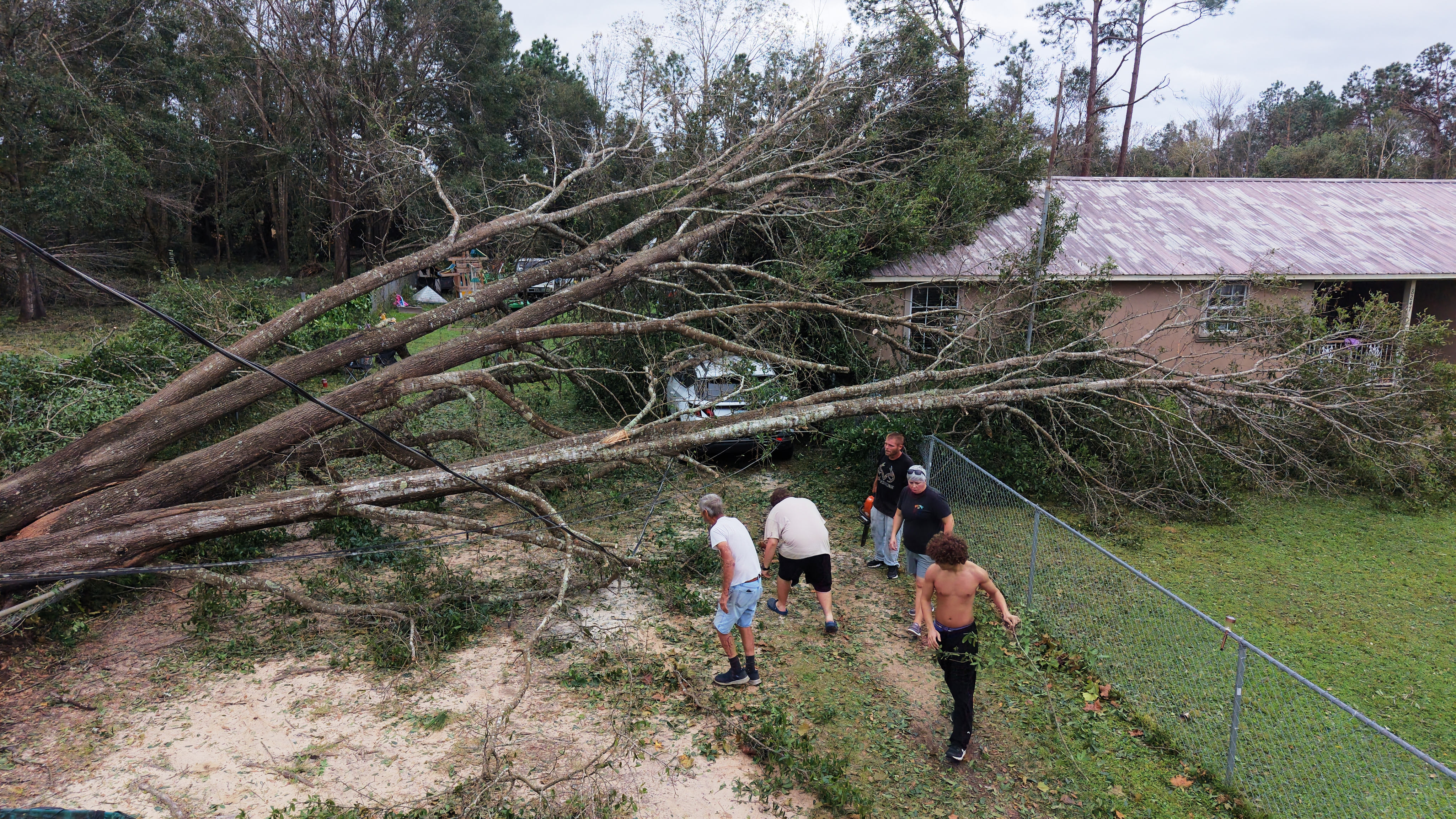 A group of residents cuts downed trees in front of a home in Milton, Florida, on Saturday. Photo: AP