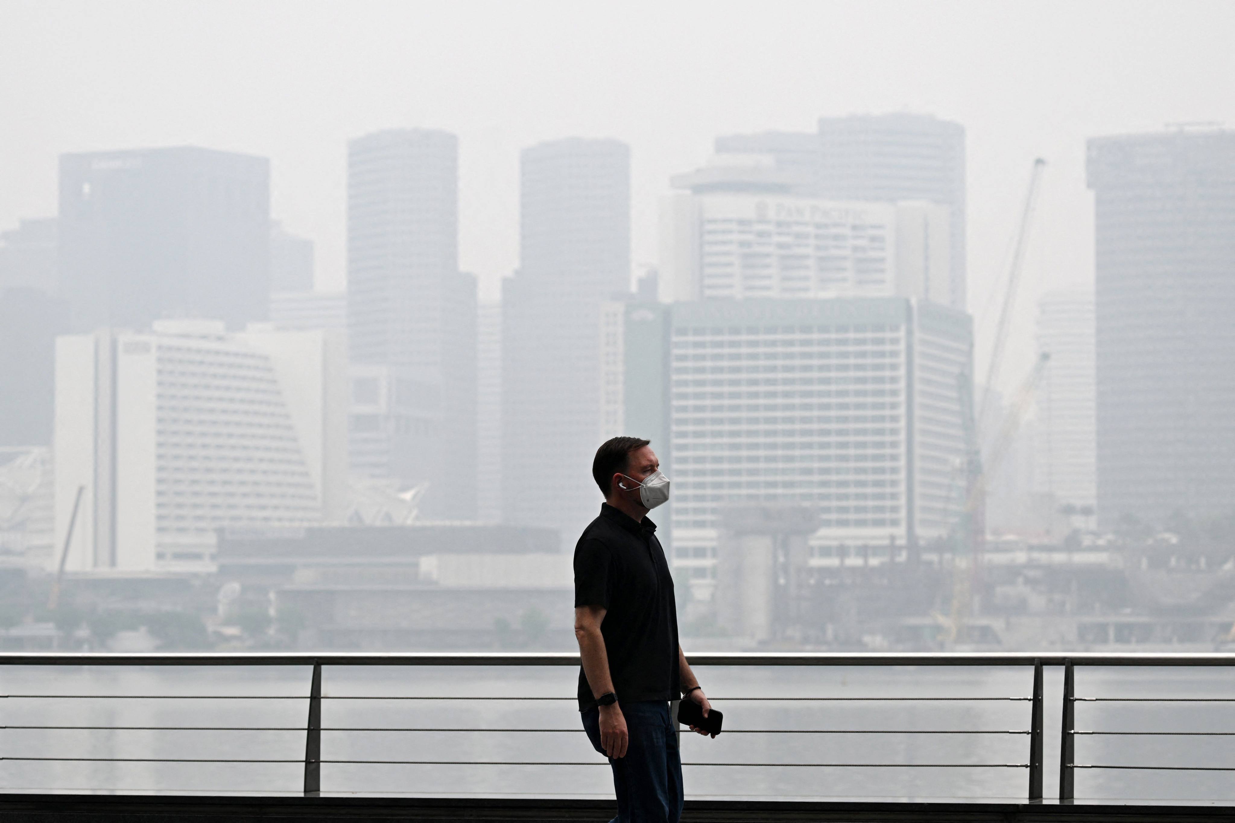 A pedestrian wearing a mask walks along the boulevard at Marina bay as buildings are seen shrouded with haze in Singapore on Monday. Photo: AFP