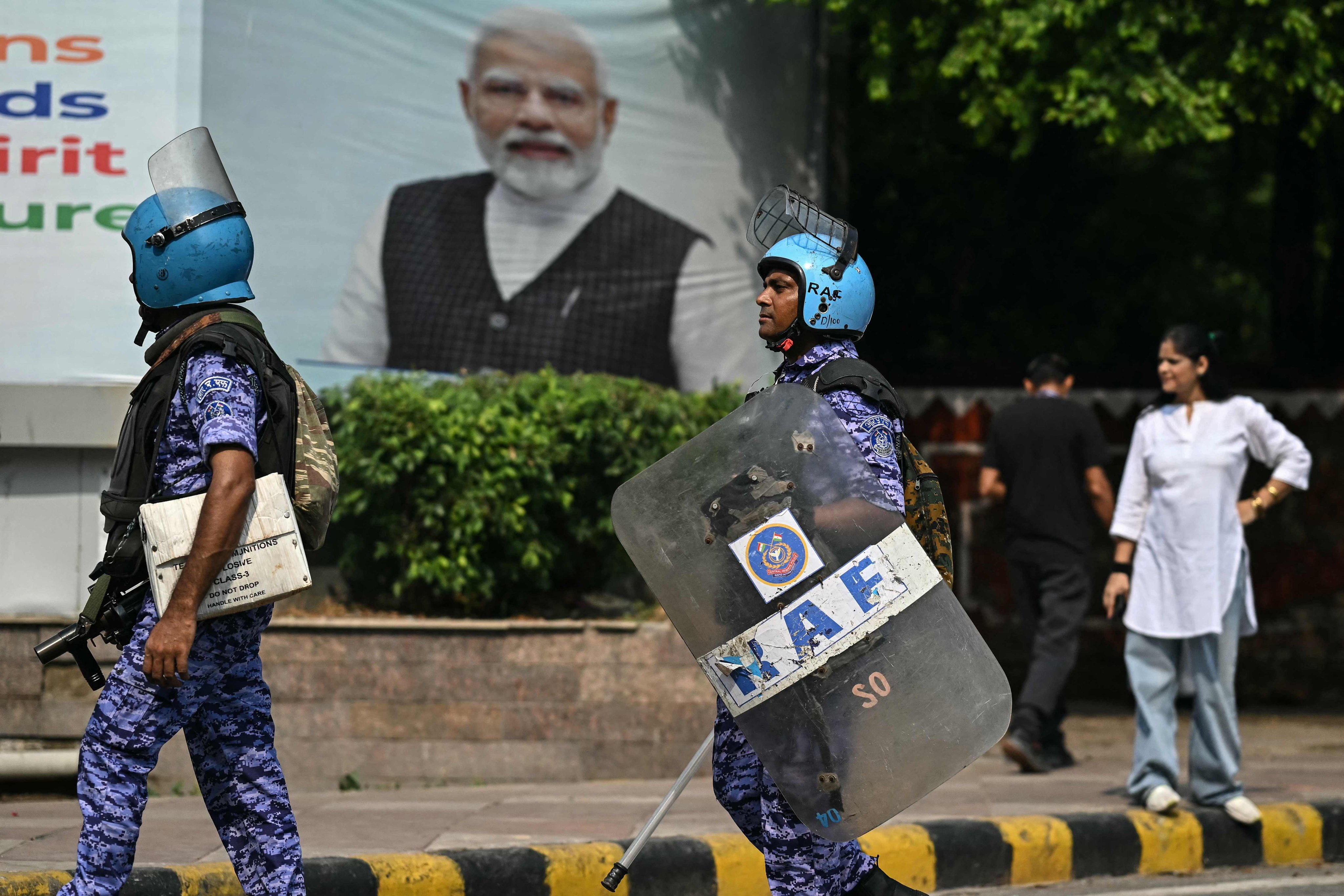 Rapid Action Force personnel walk past a portrait of Prime Minister Narendra Modi during an opposition protest in New Delhi, India, on Monday. Photo: AFP