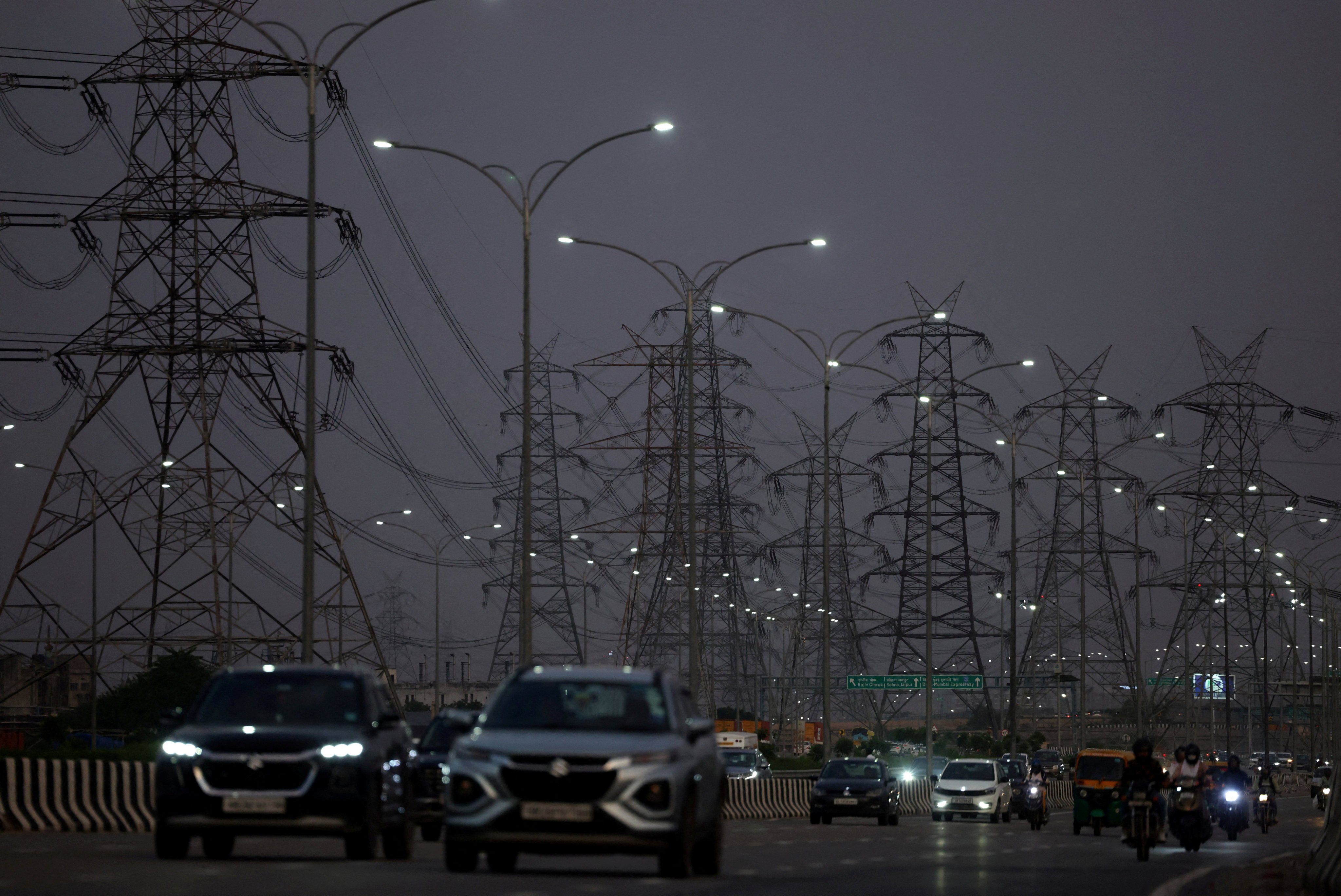Vehicles move past electricity pylons in Gurugram, India. The nation is struggling to keep up with energy demands. File photo: Reuters