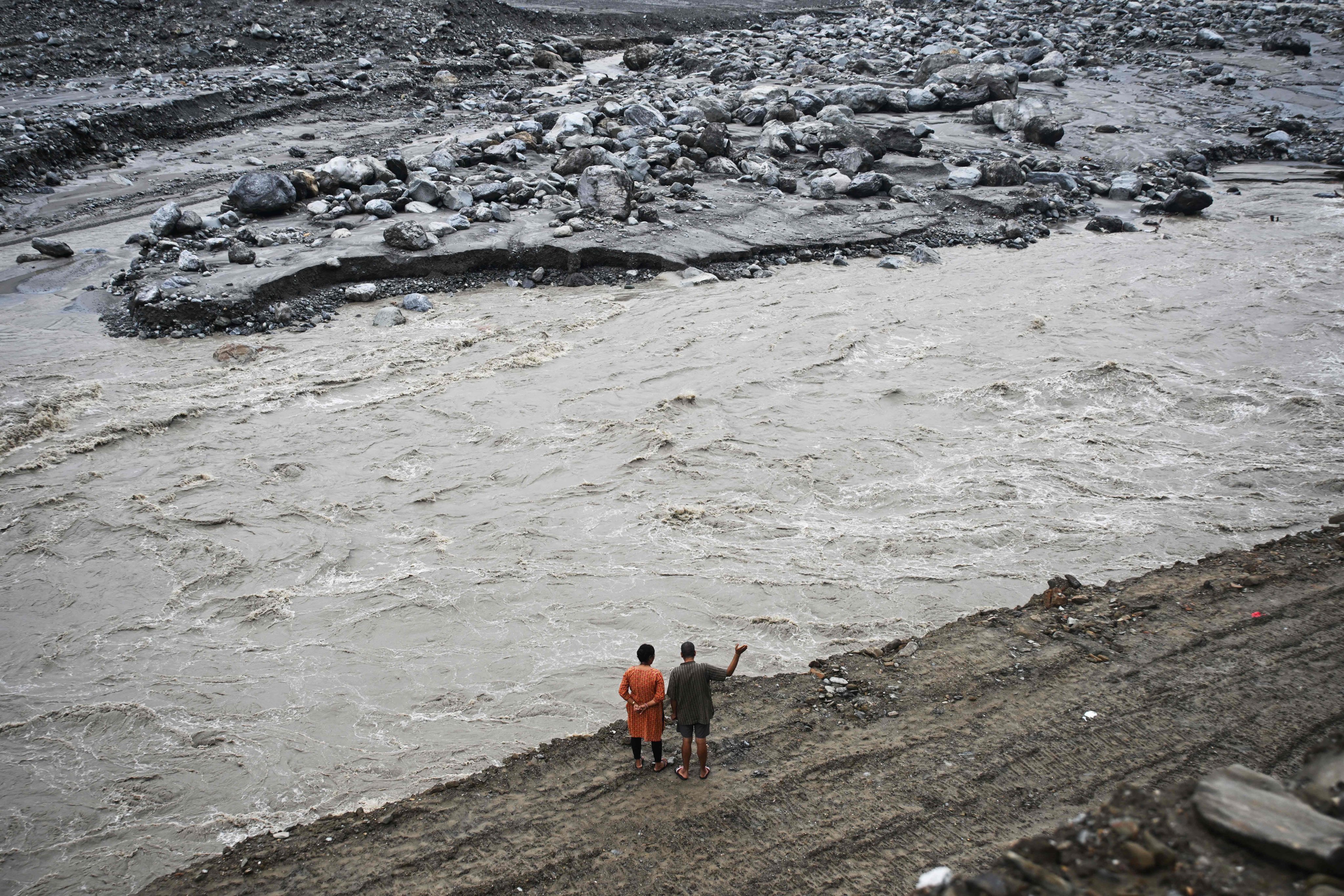 A couple stands along a river in the aftermath of the August 26 flash floods at Betrawoti Bazaar in Nepal’s Nuwakot district last month. Photo: AFP