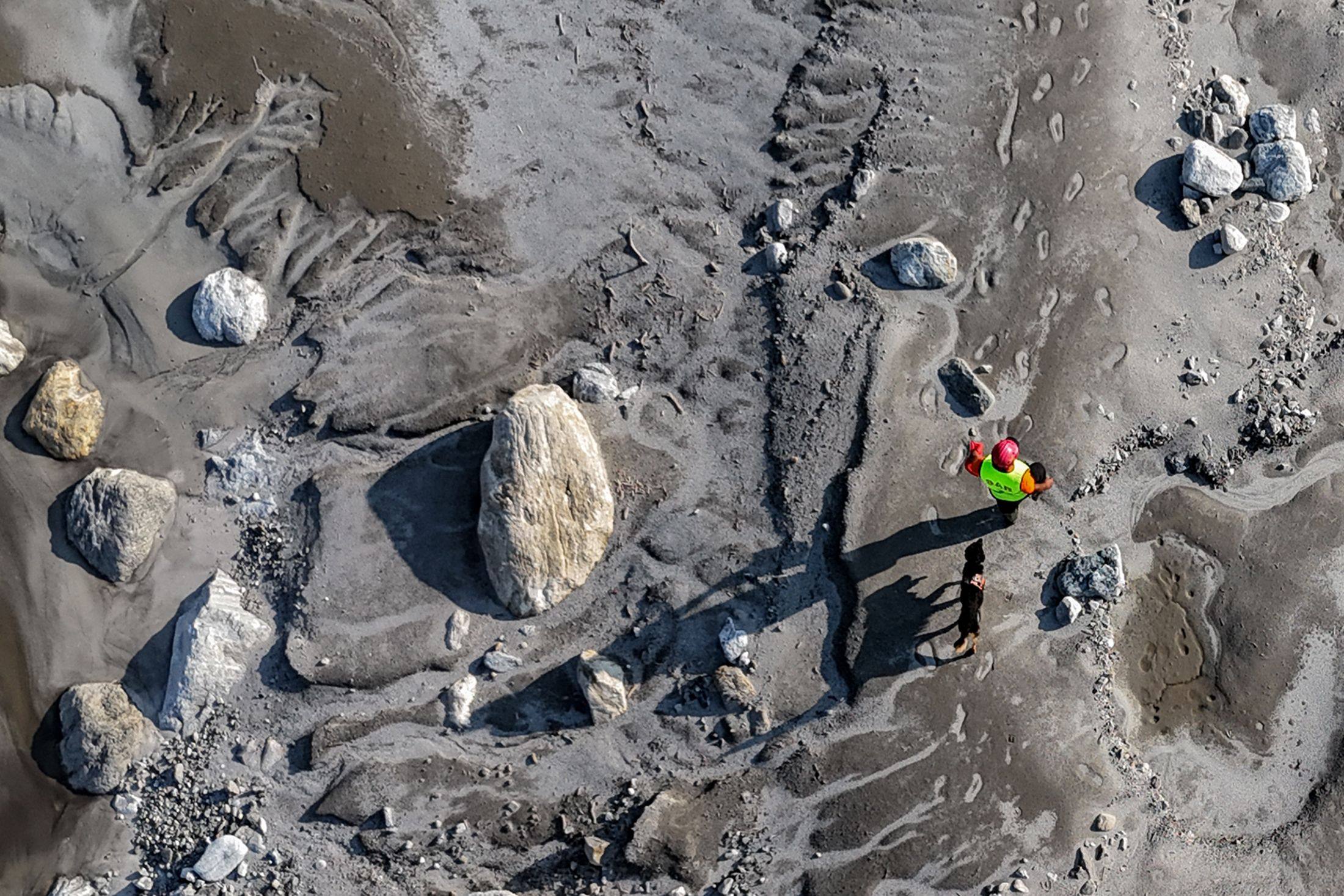 An aerial view shows a search and rescue team member, along with a sniffer dog, looking for missing people on the banks of the Trishuli River in Nepal’s Nuwakot district last month. Photo: AFP