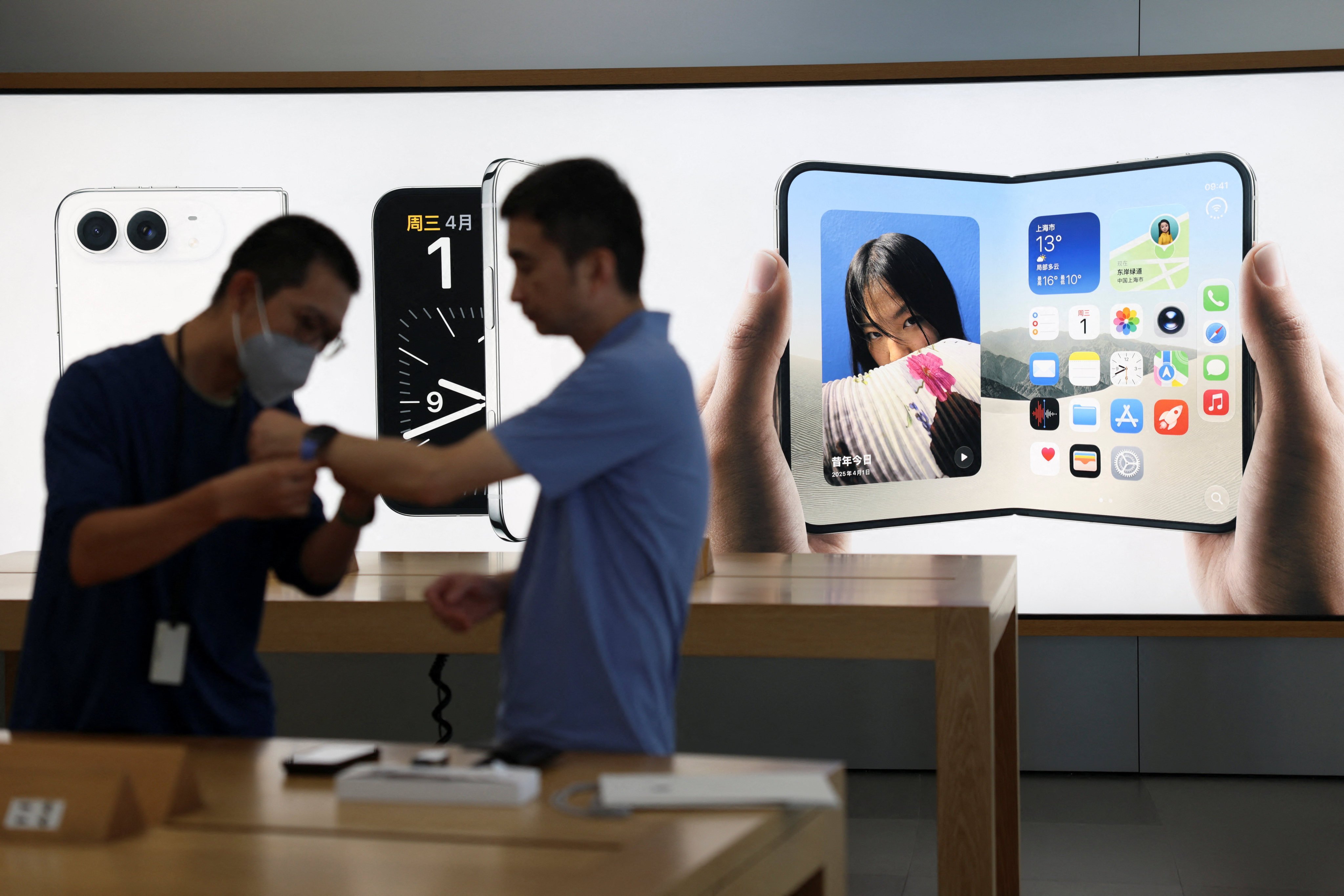 A staff member attends to a customer near an advertisement for the iPhone Duo at an Apple Store in Beijing. Photo: Reuters