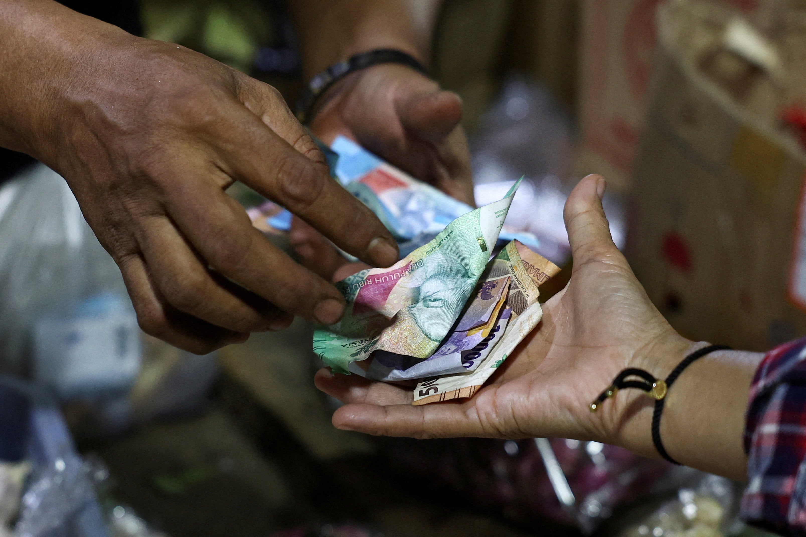 A vendor and customer exchange Indonesian rupiah banknotes. Photo: Reuters