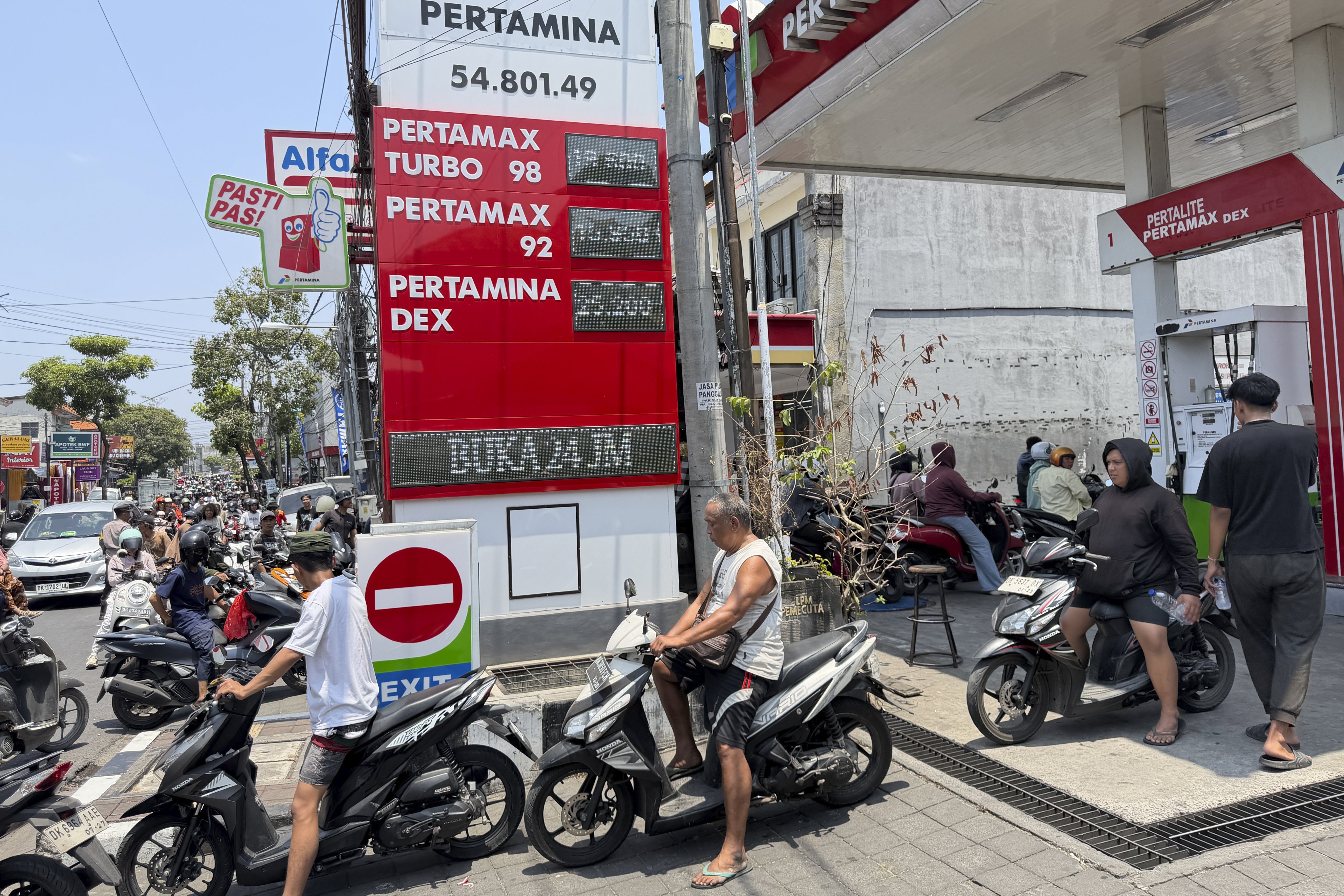 Motorcyclists form a long queue stretching down the road to refuel at a petrol station in Denpasar, Bali, on Tuesday. Photo: EPA