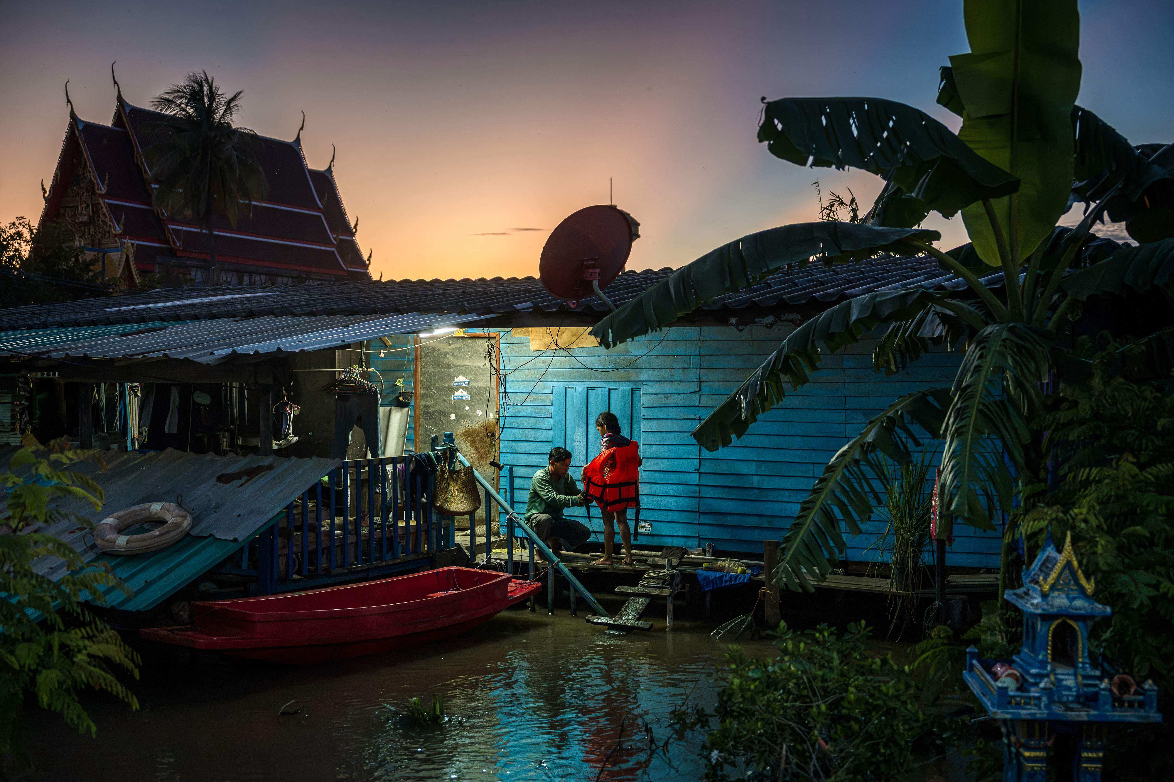 A father removes a flotation vest worn by his daughter in front of their flooded home in the central Thai province of Ayutthaya on October 7. Photo: AFP