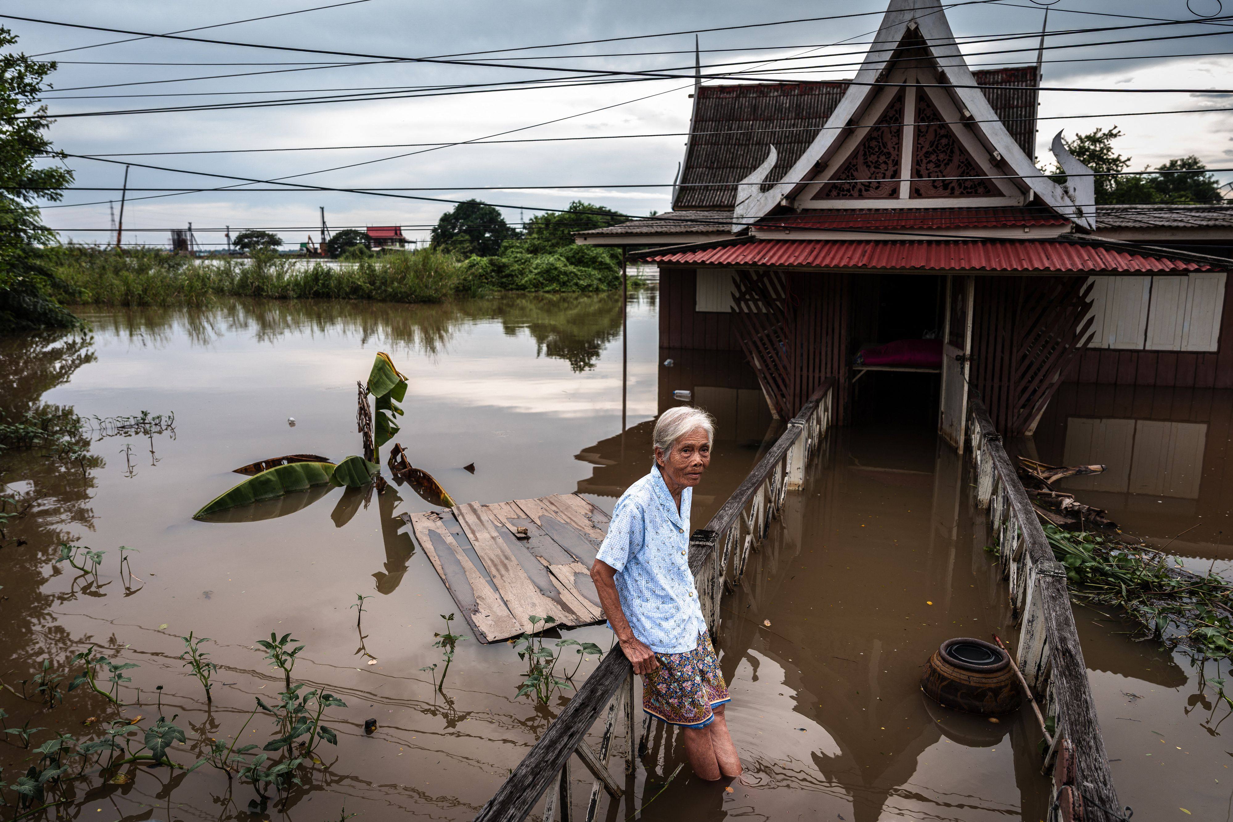 Thai retiree Samang Meewongsong, 87, sits on the wooden porch of her flooded home in Ayutthaya province on October 6. Photo: AFP