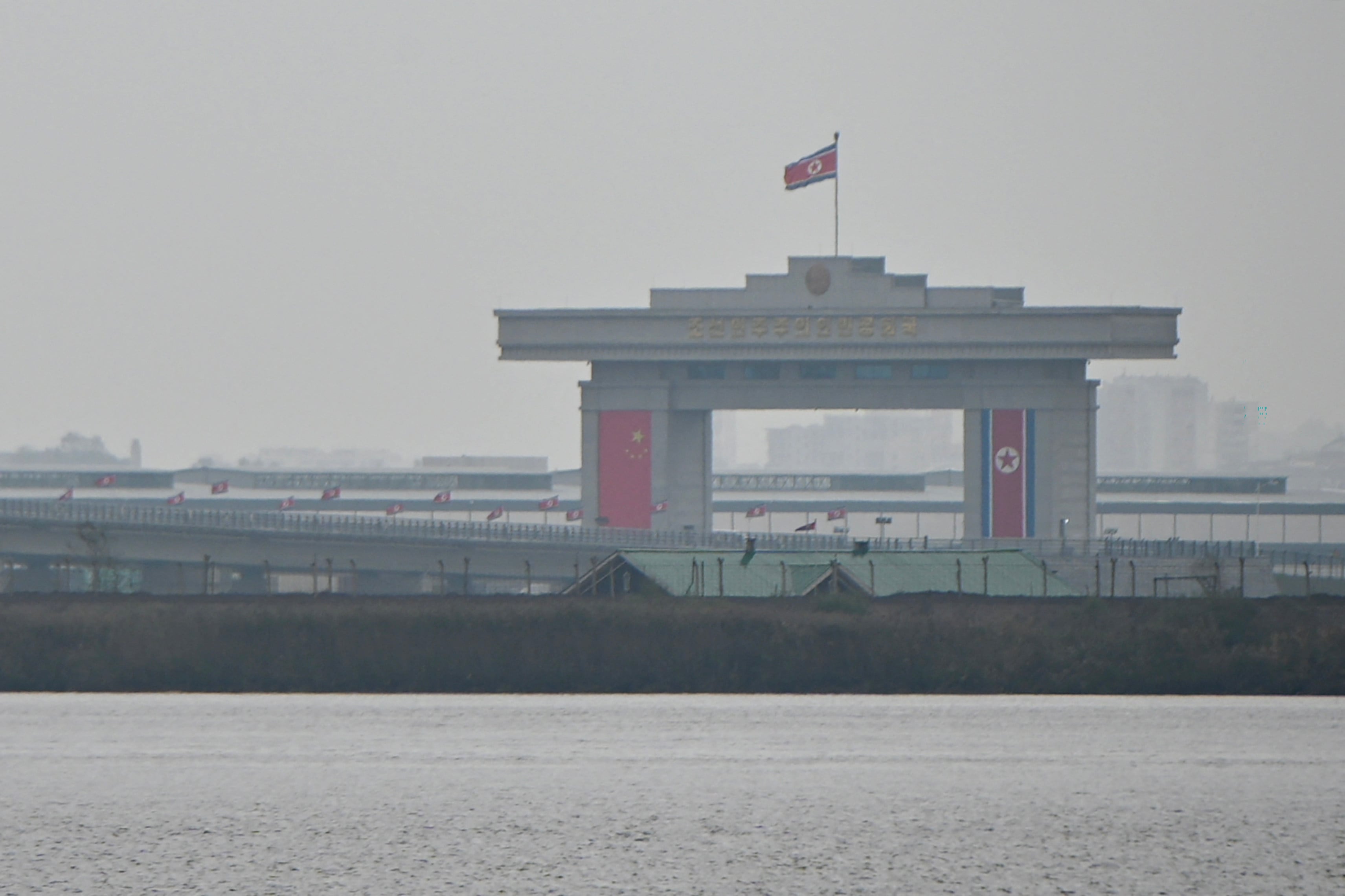 A general view shows the North Korean side of a new cross-border bridge linking China and North Korea, as seen from Dandong, Liaoning Province, on October 15, 2026. A new four-lane road bridge linking China and North Korea finally opened on October 15, 12 years late, enabling the Asian giant and its isolated nuclear-armed neighbour to step up cross-border trade substantially. (Photo by Michael ZHANG / AFP)
