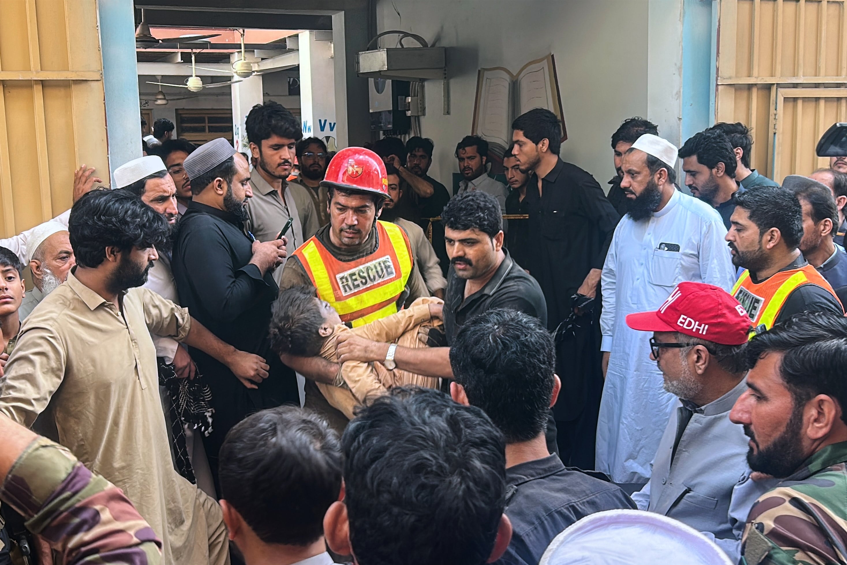 A rescuer carries an injured child following a school roof collapse in Peshawar, Pakistan, on Thursday. Photo: AP
