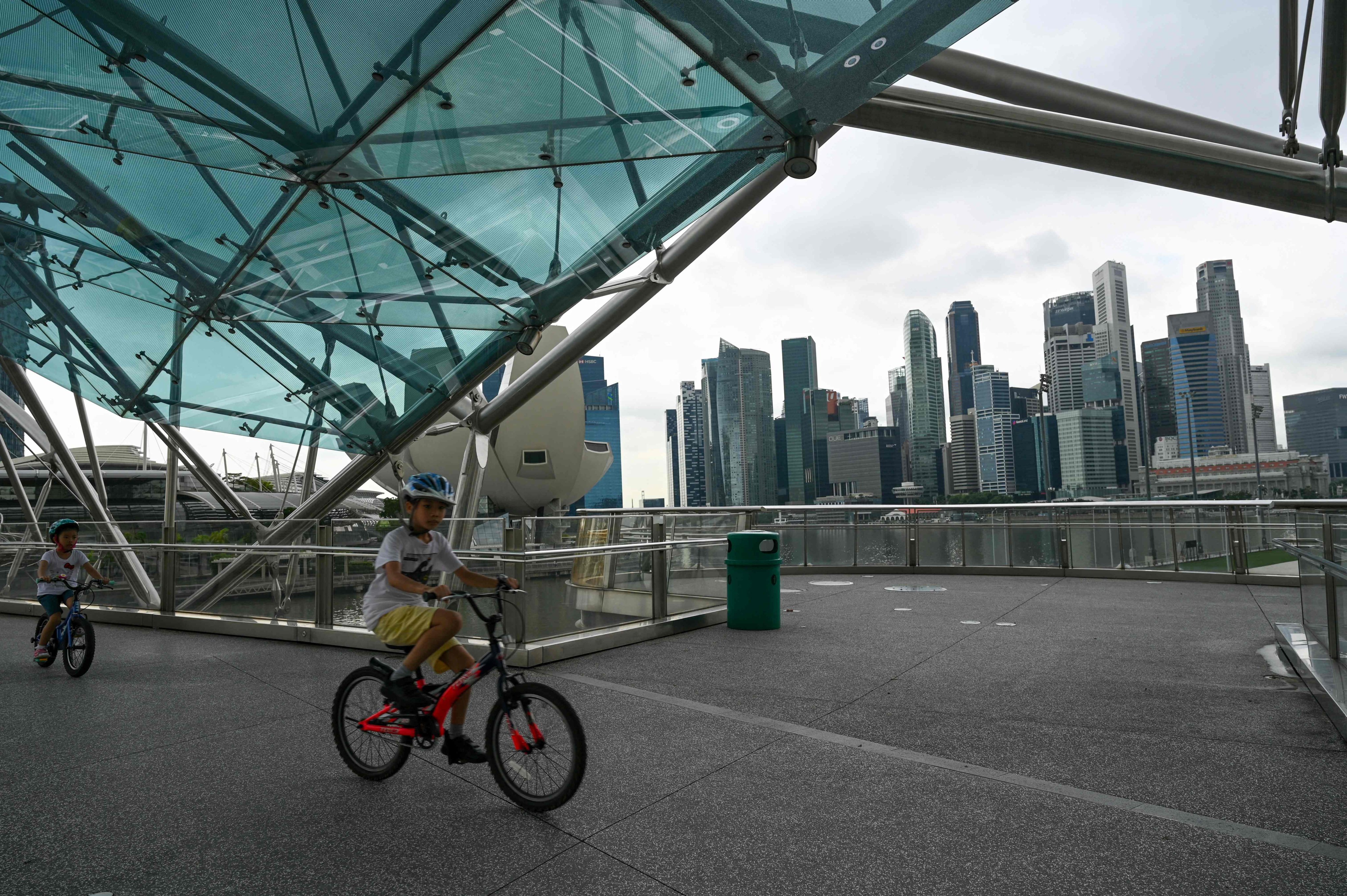 Children ride bicycles along the Helix Bridge, with a view of the financial district, in Singapore in 2022. Photo: AFP