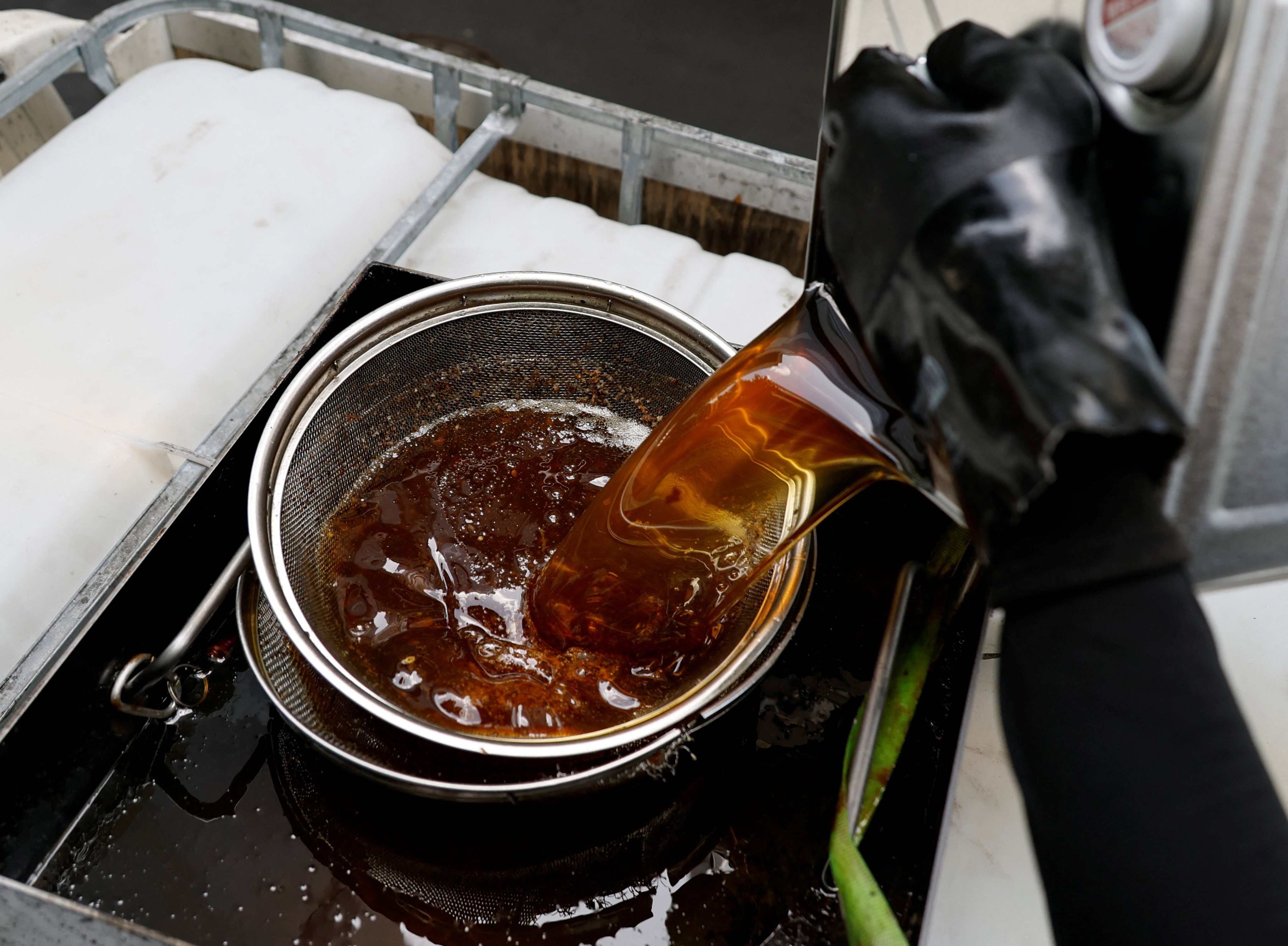 A worker from a firm collecting used cooking oil to produce sustainable aviation fuel pours oil from a Tempura Ten-ichi restaurant into a tank in Tokyo on April 22. Photo: Reuters