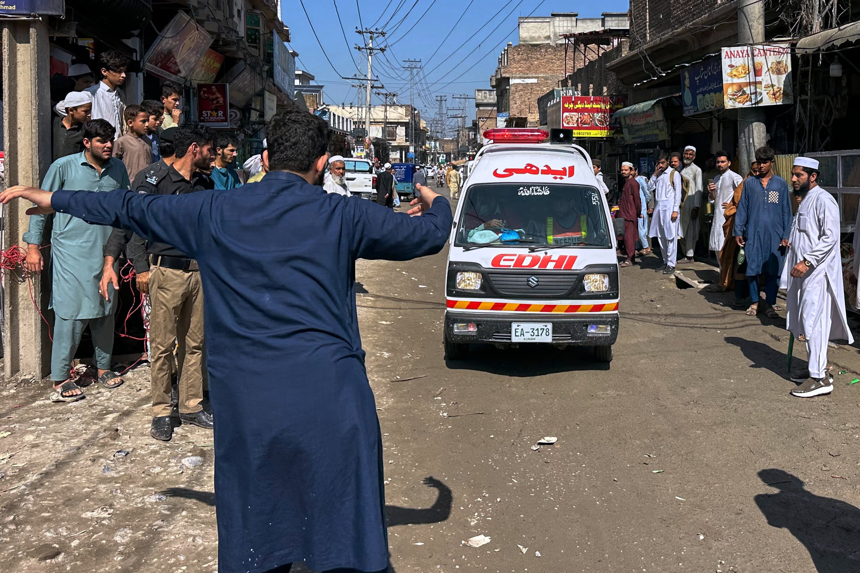 A volunteer directs traffic for an ambulance carrying victims of a school roof collapse in Peshawar, Pakistan, on Thursday. Photo: AP
