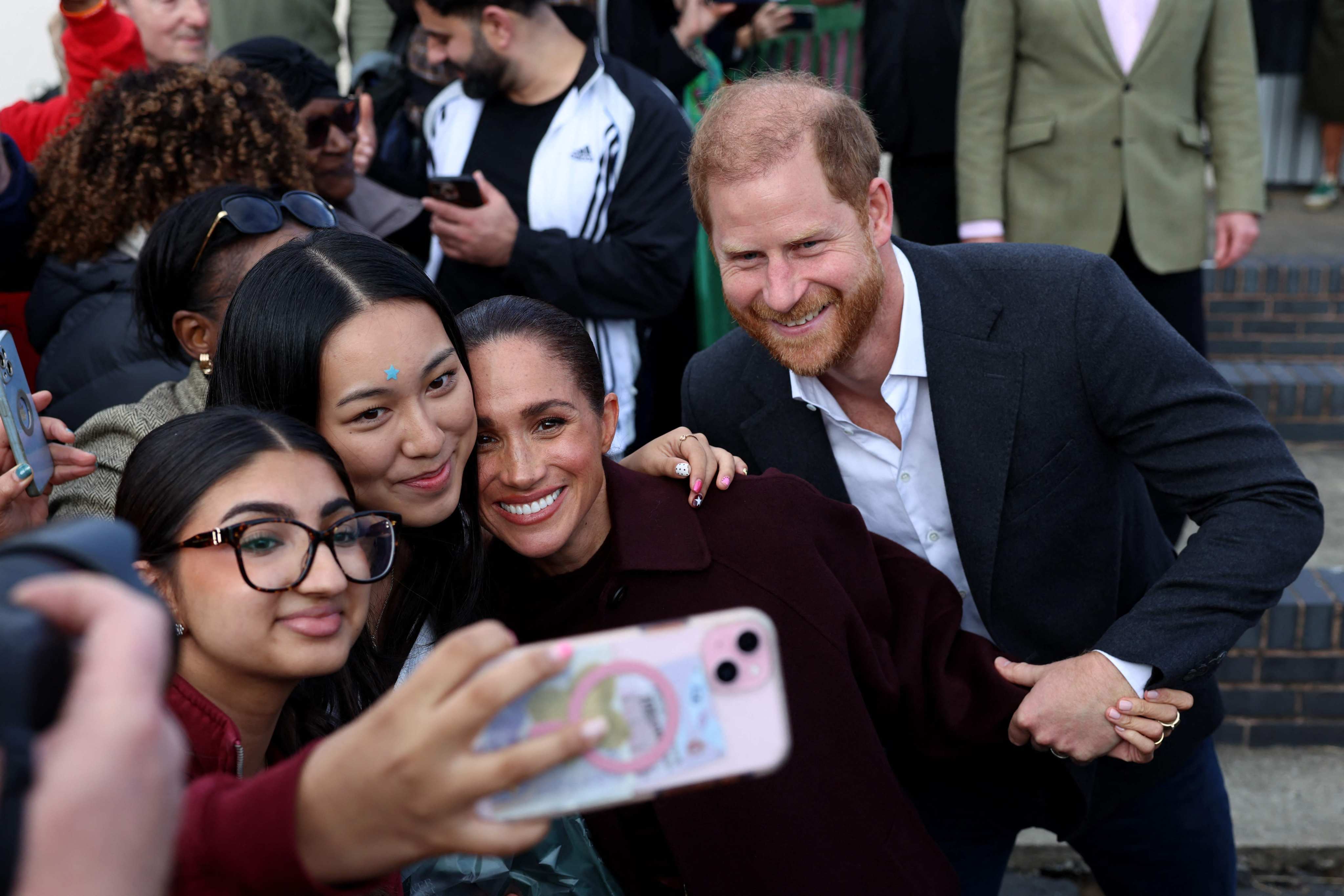 Britain’s Prince Harry and Meghan, Duchess of Sussex, pose for a selfie with fans in Nottingham on Thursday. Photo: AFP