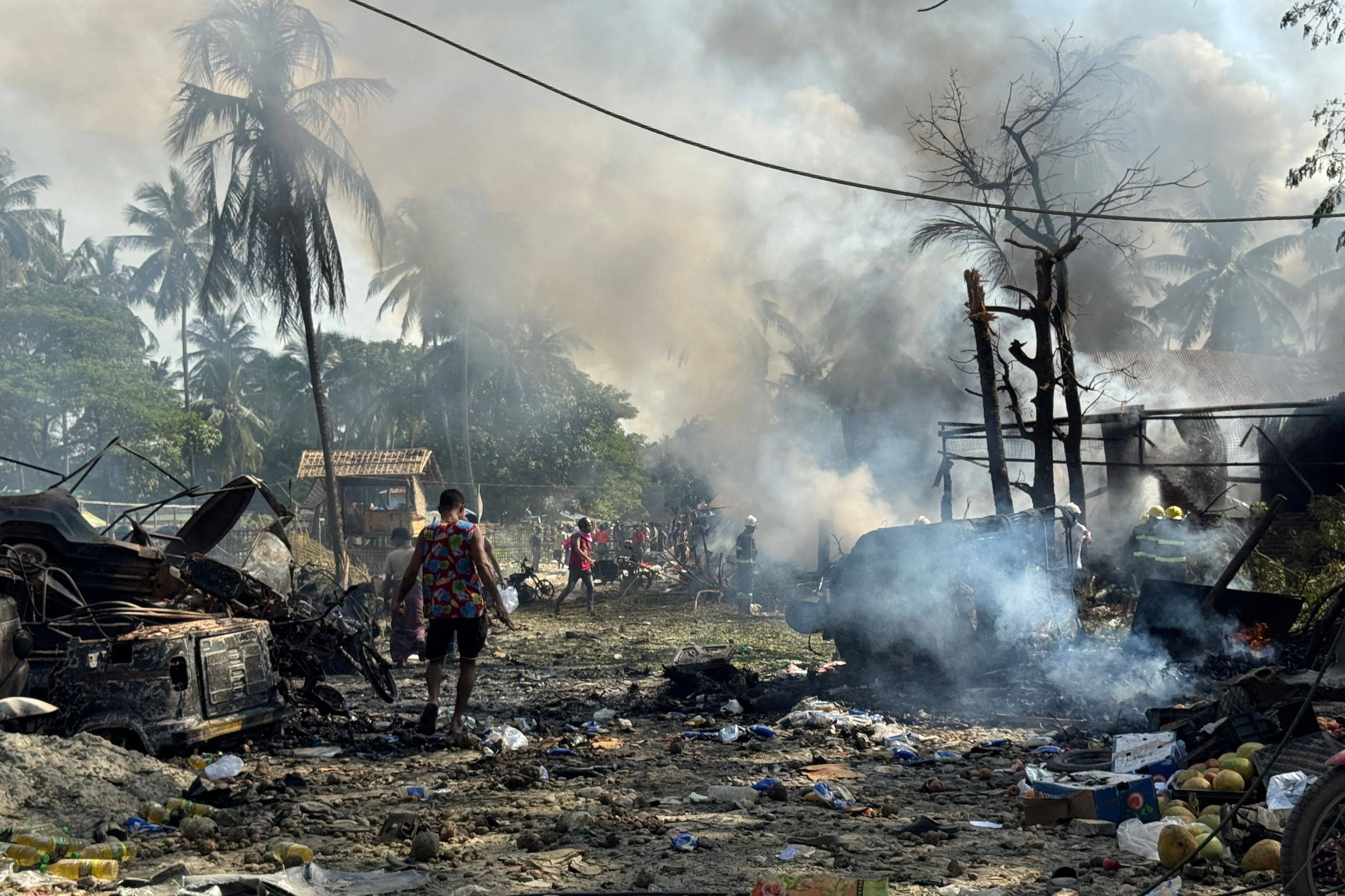 People walk through smoke and smouldering debris following a Myanmar military air strike on a market and adjacent bridge in Kyauktaw, Rakhine state, last month. Photo: AFP