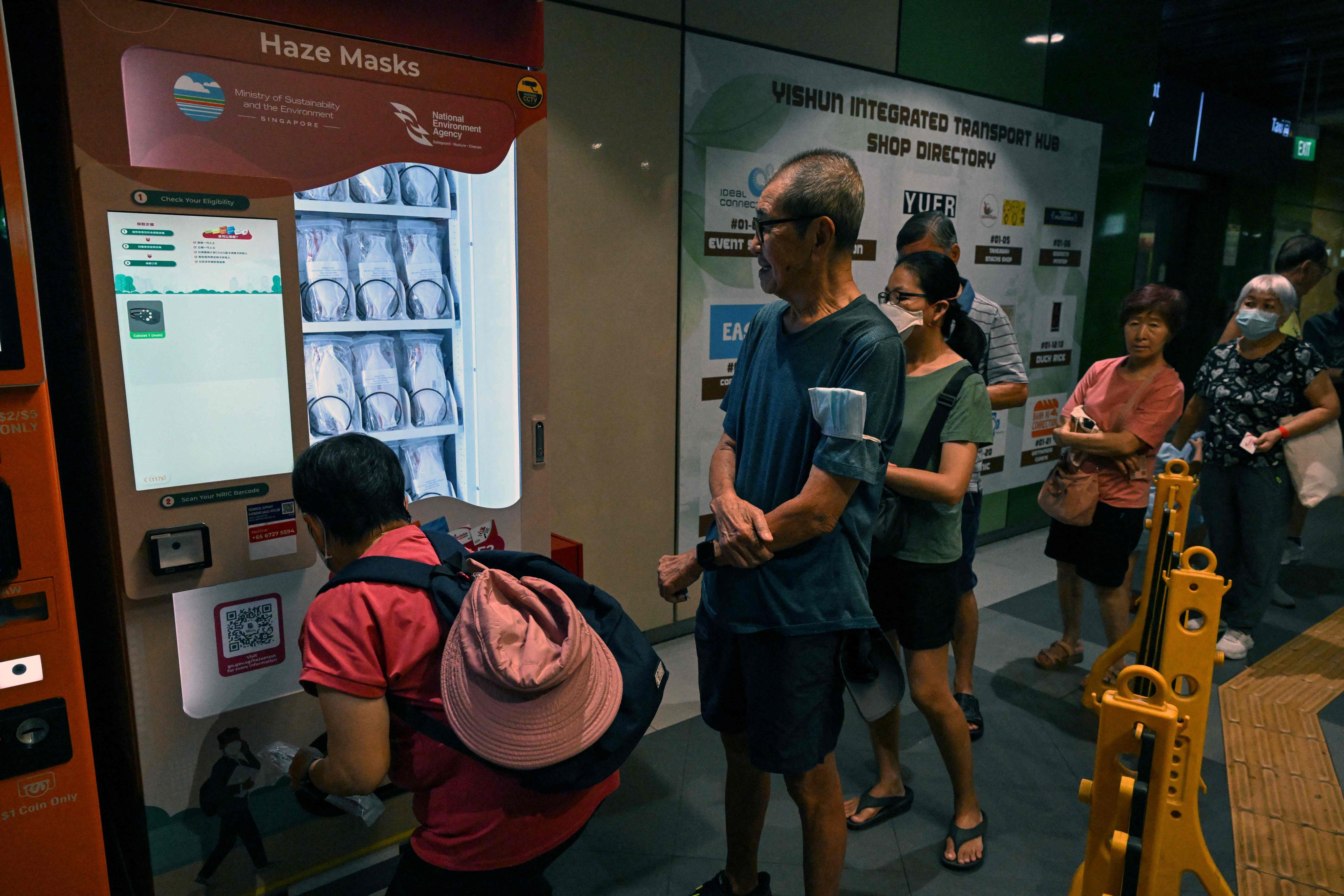 People get protective face masks from a vending machine at a bus interchange in Singapore on Friday as haze from Indonesia’s wildfires shrouds the city state. Photo: AFP