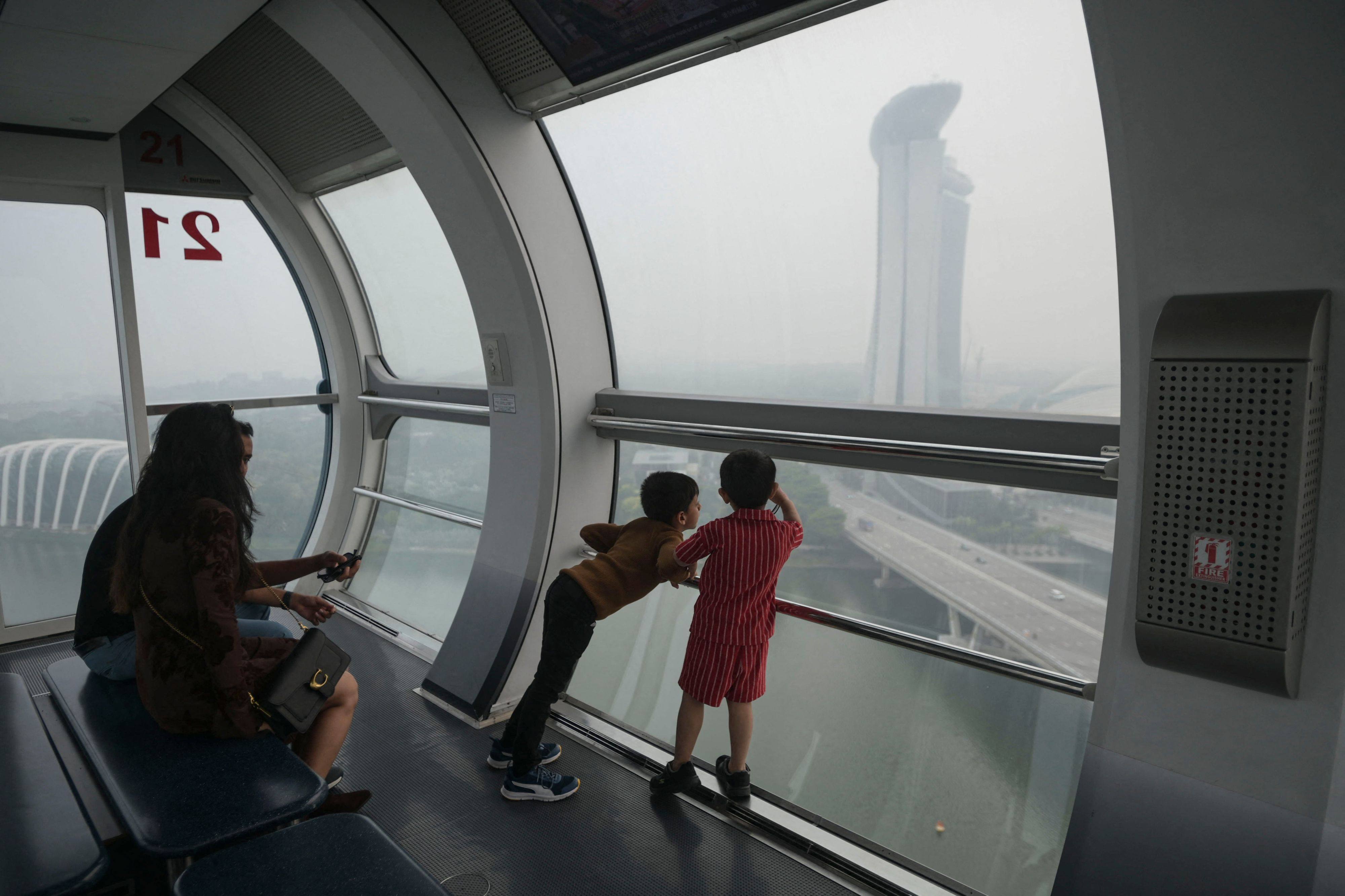 A family looks out of a cabin in the Singapore Flyer in Singapore on Thursday as the country continues to be shrouded in haze caused by fires in Indonesia. Photo: AFP