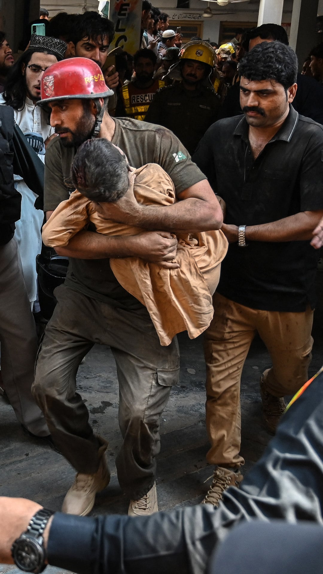 A rescuer (C) carries a child during a search operation after a roof collapsed at a school in Peshawar on October 15, 2026.