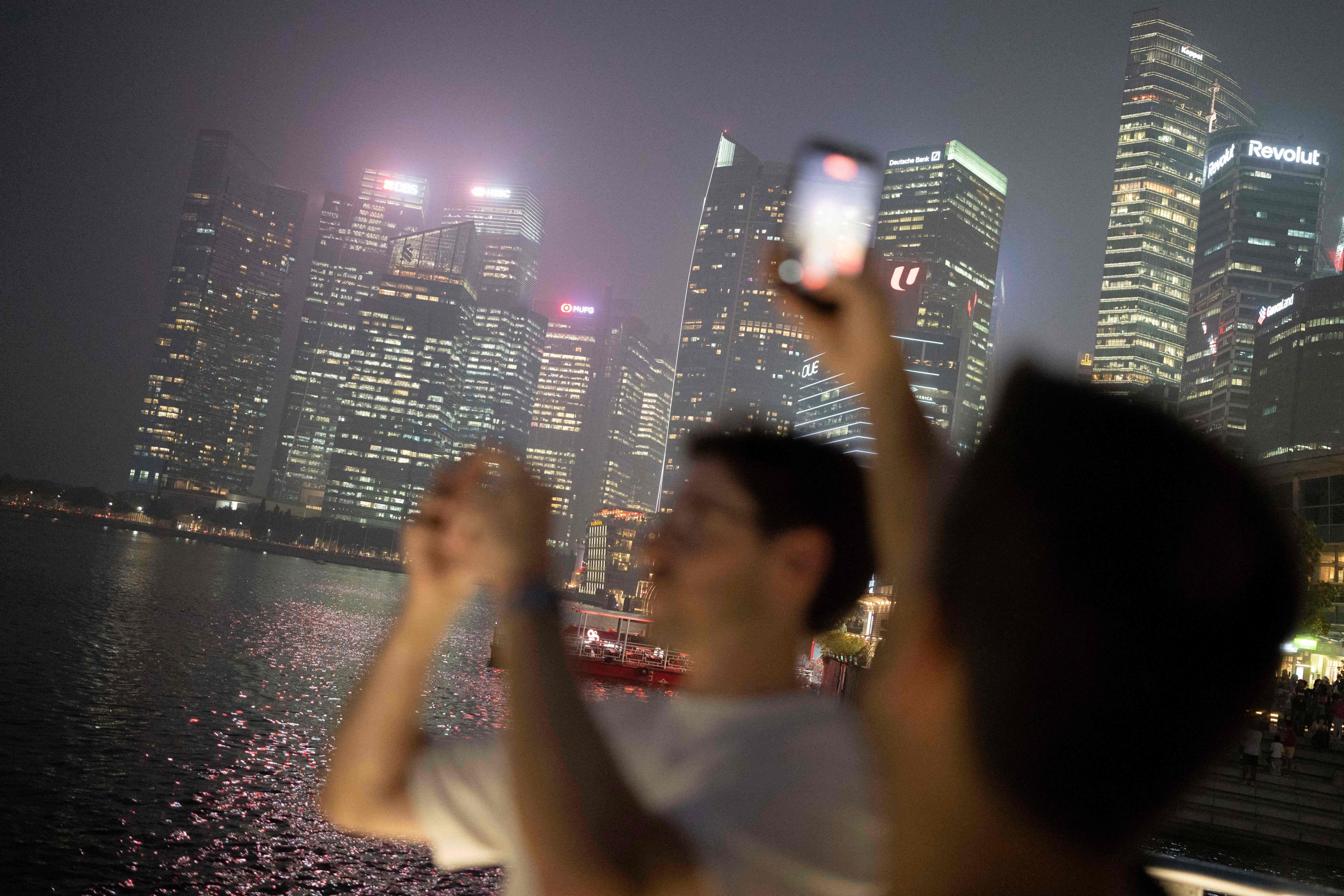 People take photographs of the Singapore city skyline on Friday. Photo: AFP