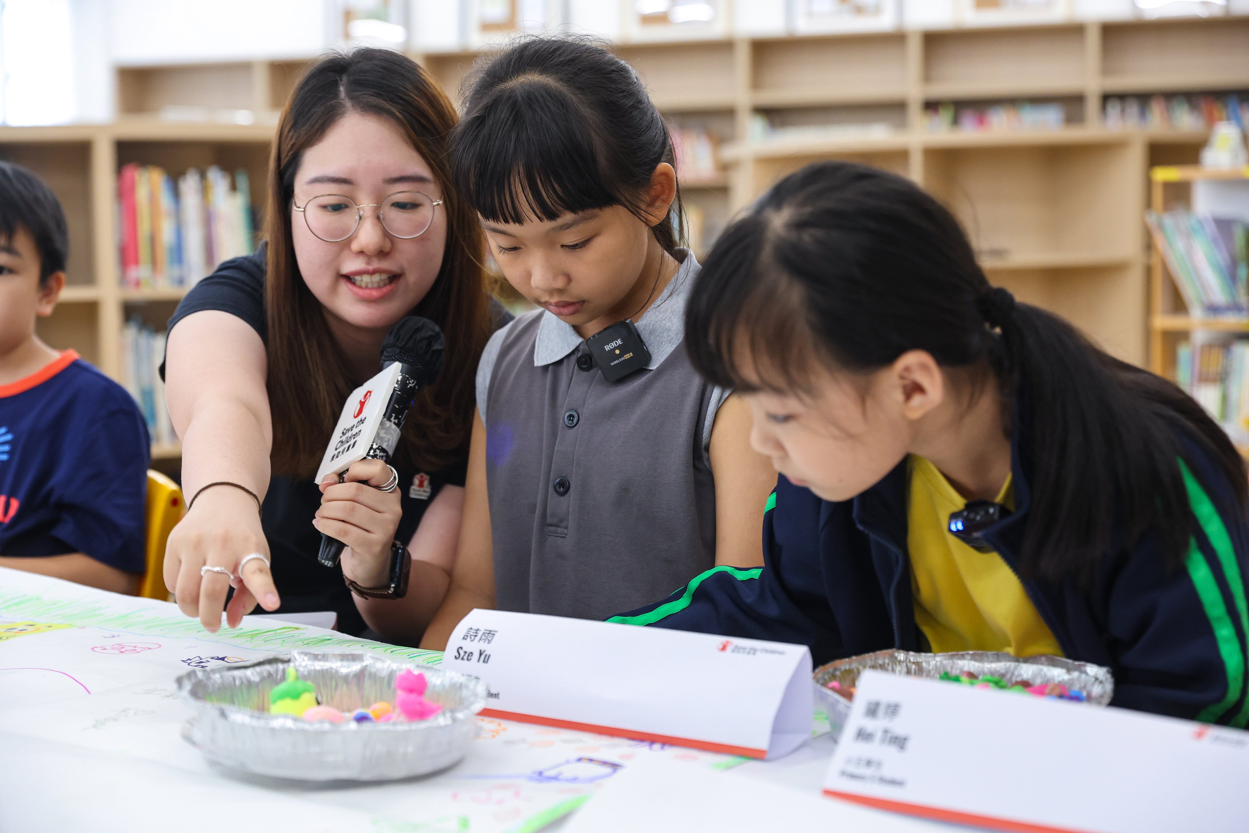 (From left) Save the Children Hong Kong project coordinator Tiffany Ho, and pupils Sze Yu and Hei Ting, at a press briefing on the NGO’s therapy programmes for young survivors of the Tai Po fire. Photo: Edmond So