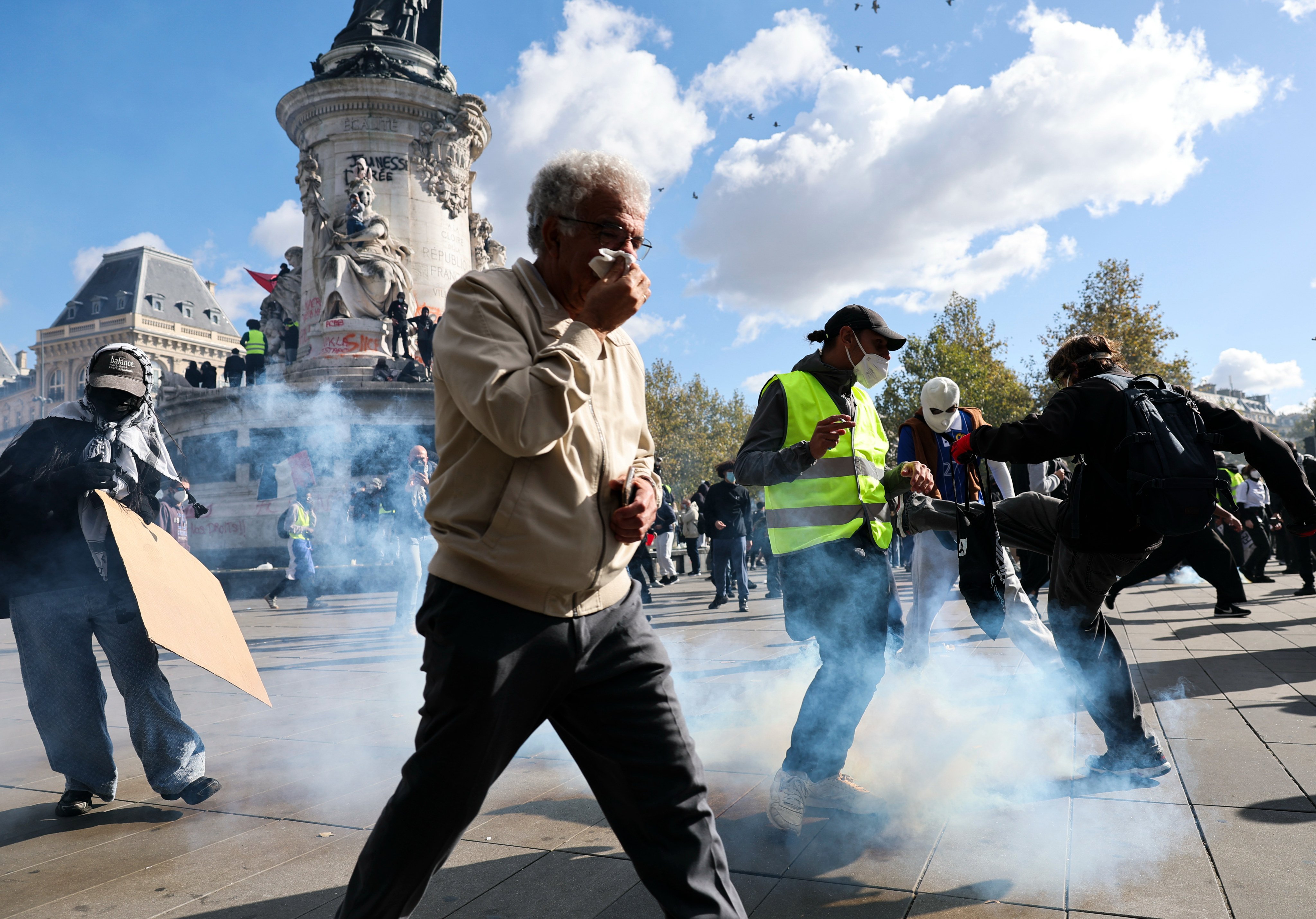 People take cover from tear gas during a protest in Paris on Saturday. Photo: Xinhua