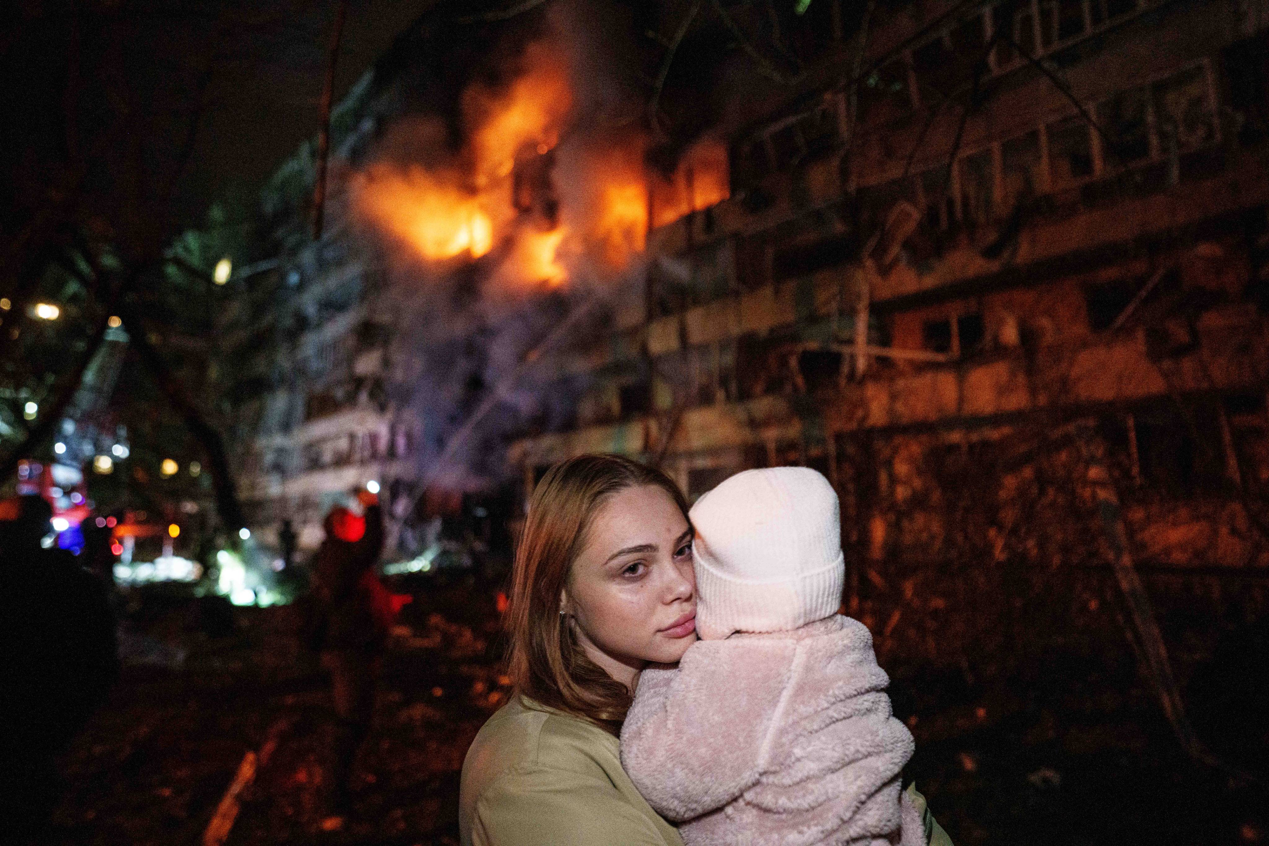 A woman holds her daughter while standing in front of a residential building damaged in a Russian missile strike in Kyiv, Ukraine, on Tuesday. Photo: AP
