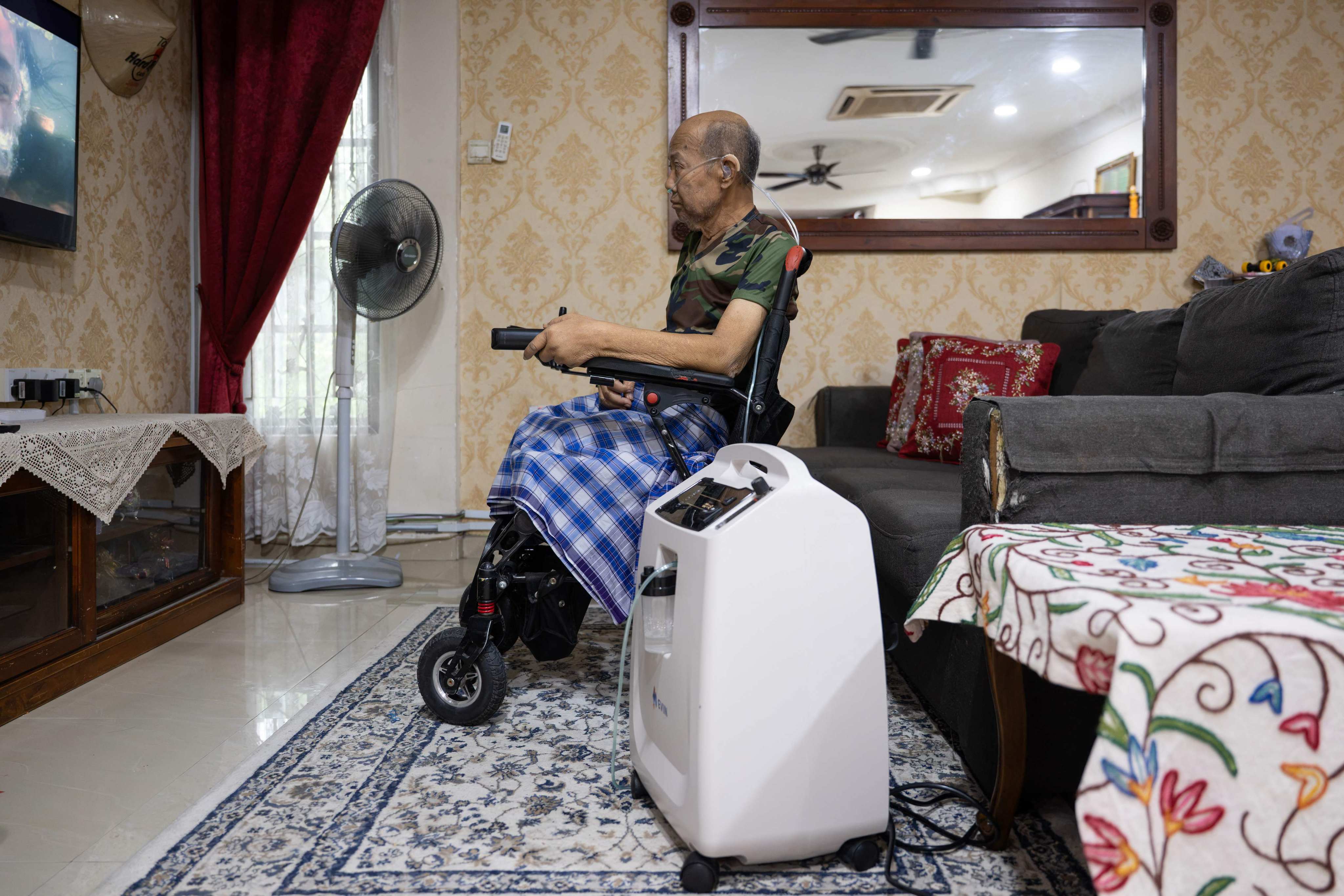 Md Noor Bin Bujang watches television while using an oxygen concentrator at his home in Rawang, Malaysia’s Selangor state, on Friday. Photo: AFP