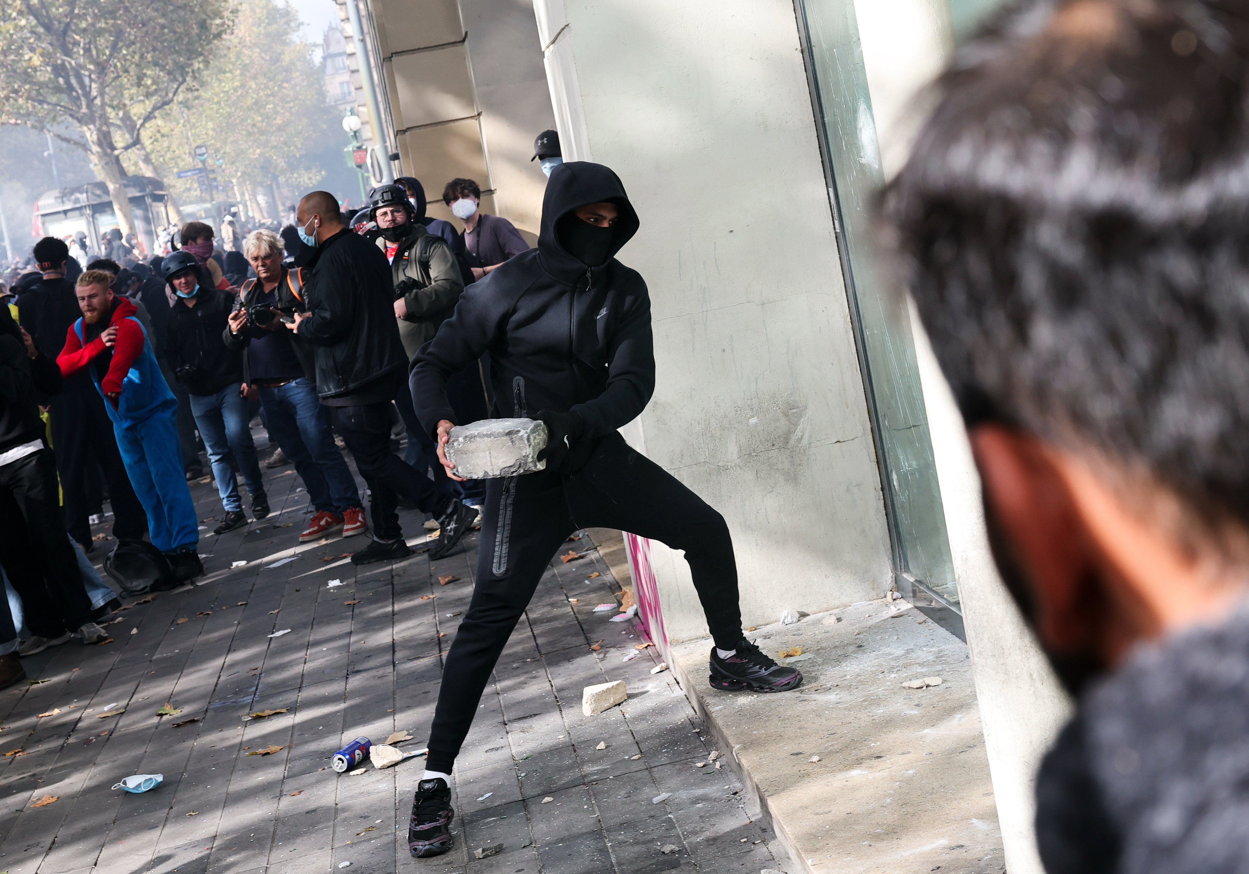 A man smashes a store window with a stone during a protest against the high cost of living in Paris, France, on Saturday. Photo: Xinhua