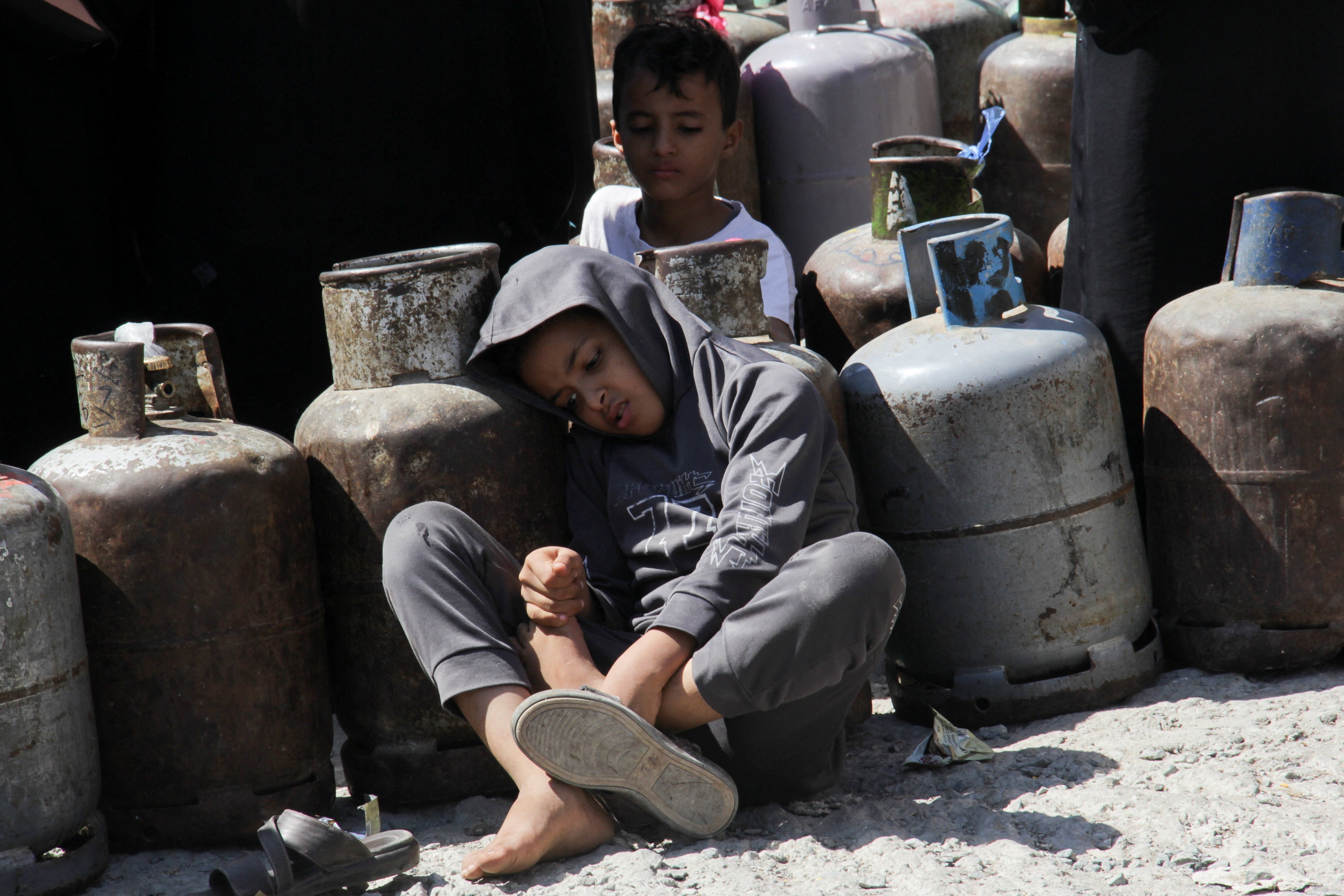 Boys sit as they wait in a queue to fill up cooking gas cylinders in the southwestern city of Taiz, the last major urban stronghold of anti-Houthi forces in the southern highland area of Yemen. Photo: Reuters