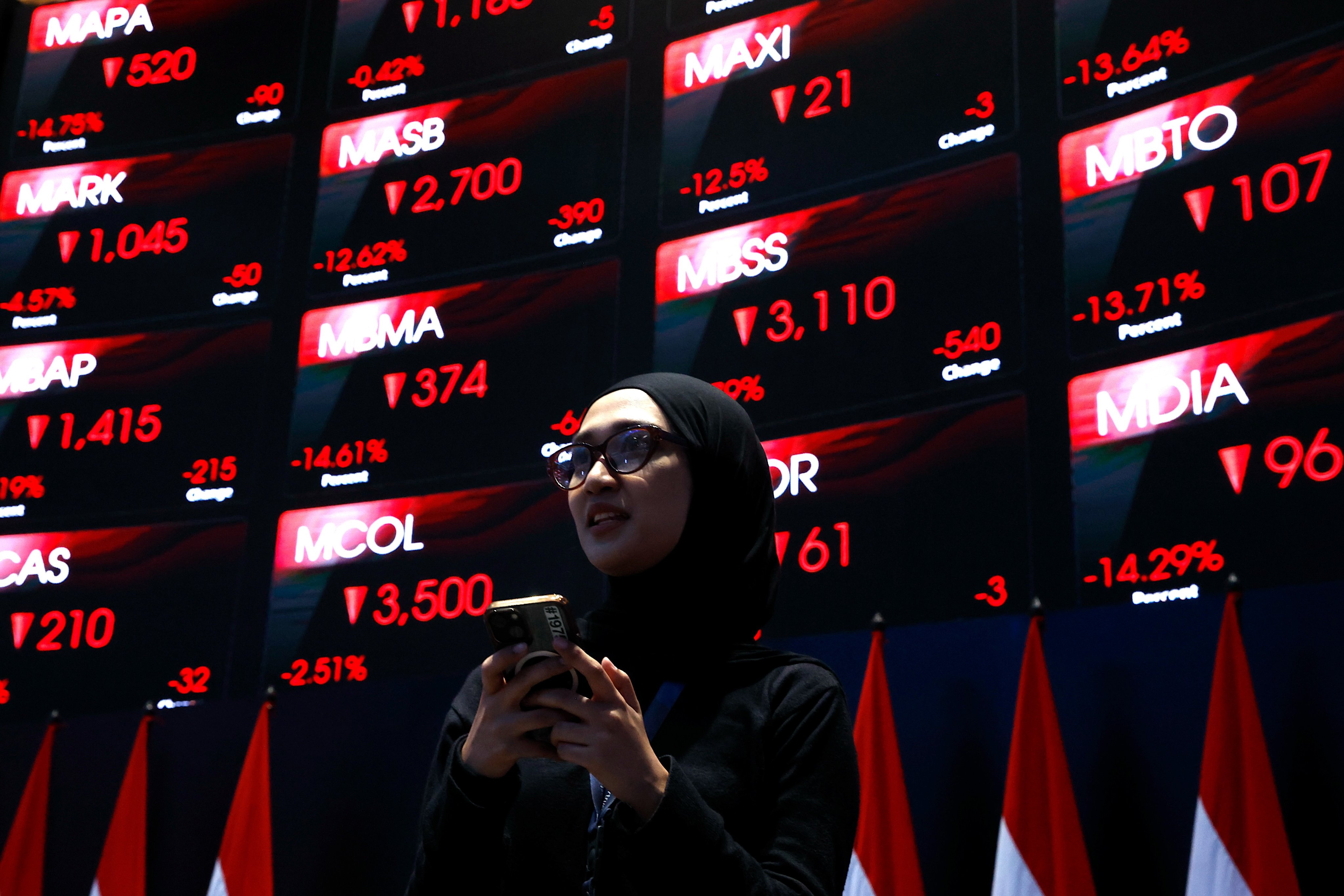 A woman stands in front of a board displaying stock prices at the Indonesia Stock Exchange building in Jakarta on Friday. Photo: EPA