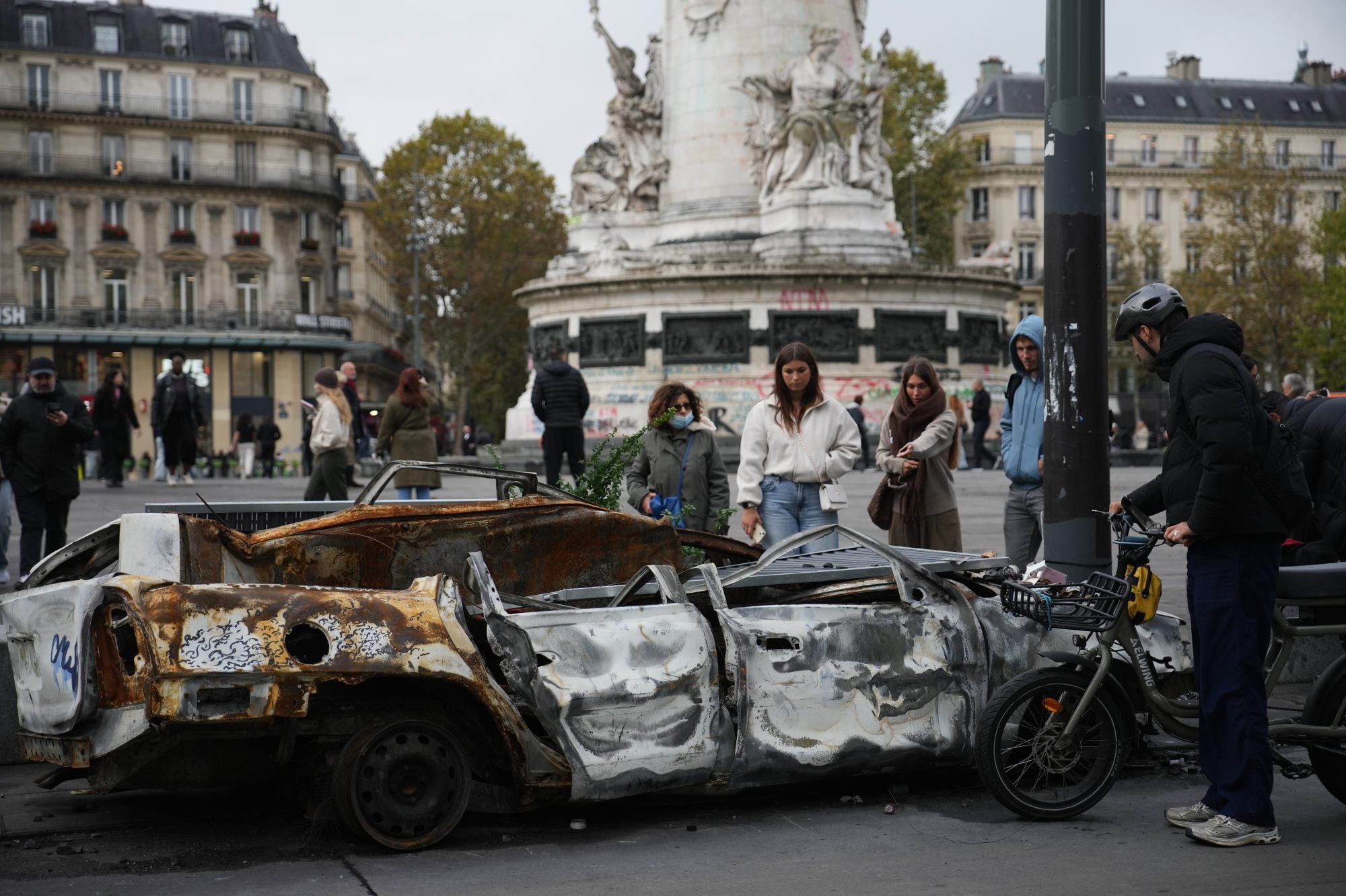 People view a burned-out car in Paris on Tuesday, days after riots erupted across the French capital. Photo: AP