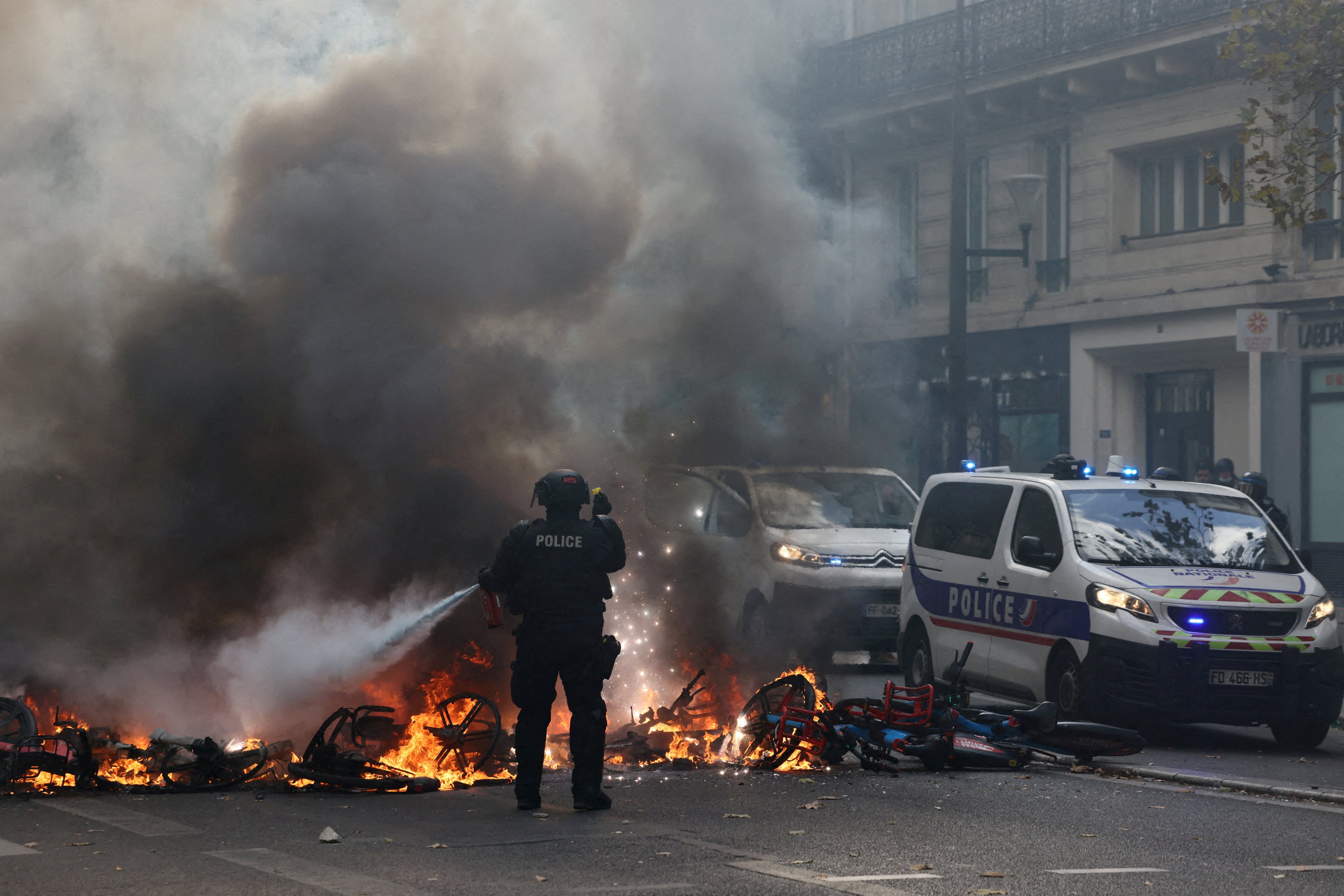 A French police officer extinguishes burning bicycles during a protest in Paris on Saturday. Photo: Reuters