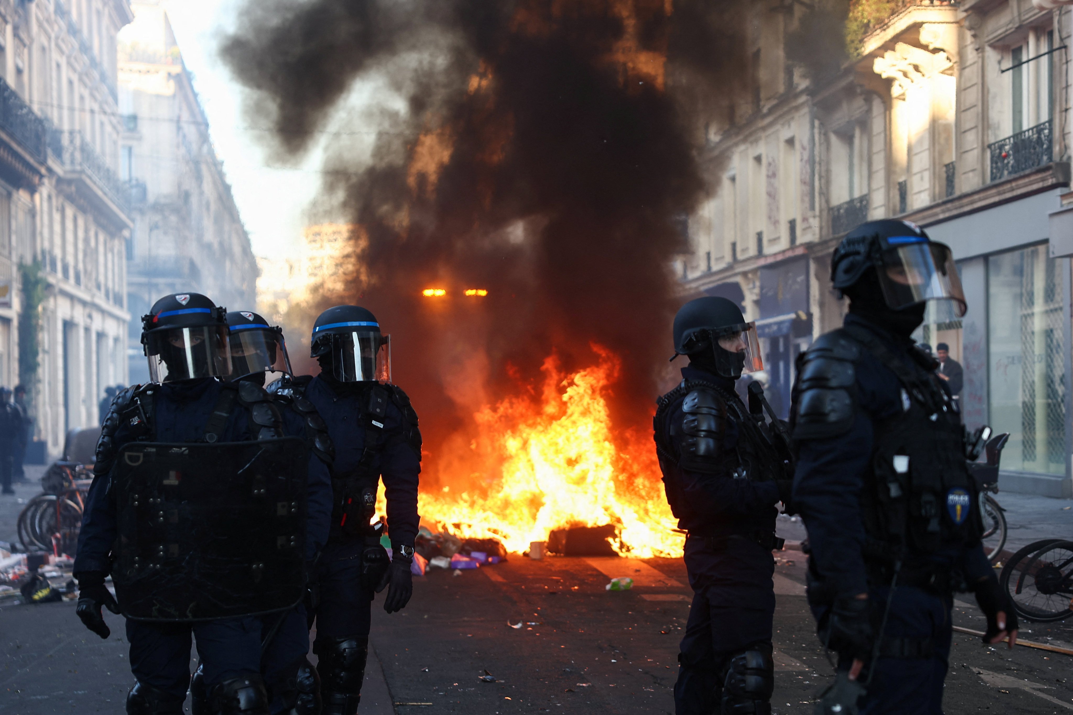 A fire burns as police officers in riot gear stand guard during civil unrest after demonstrations in Paris on October 18. Photo: Reuters