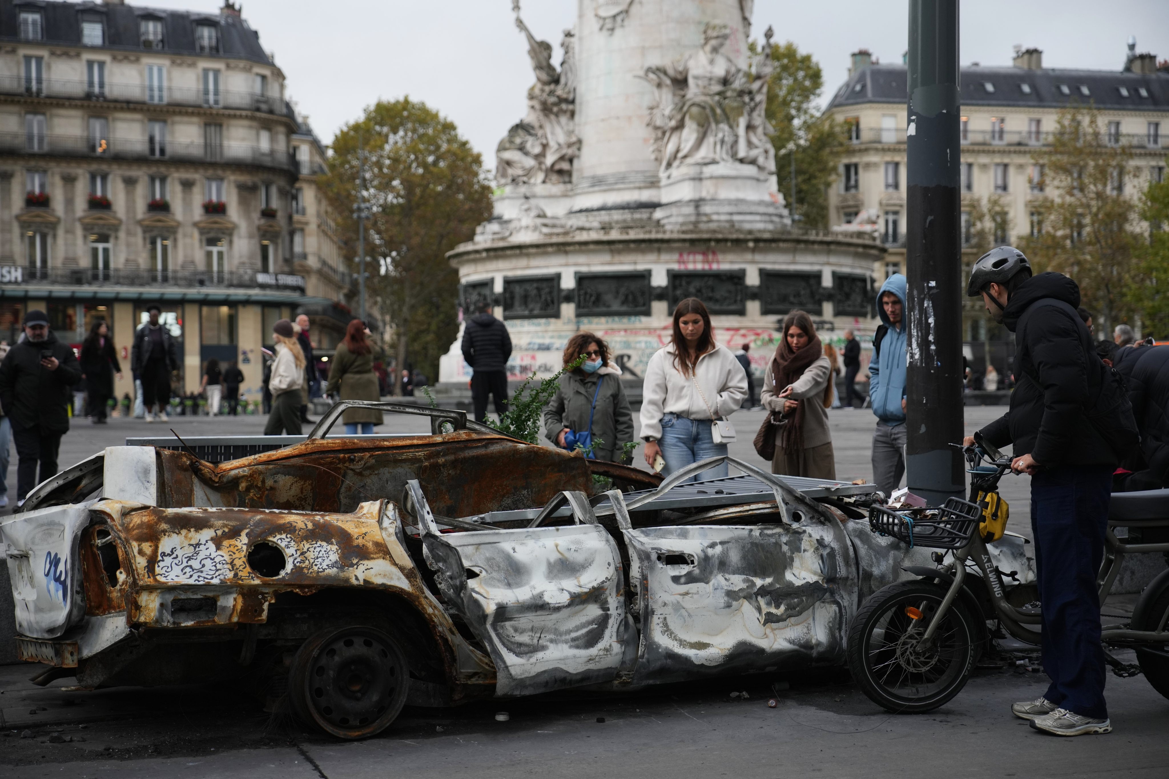 People watch a burned-out car in Paris on Tuesday. Photo: AP