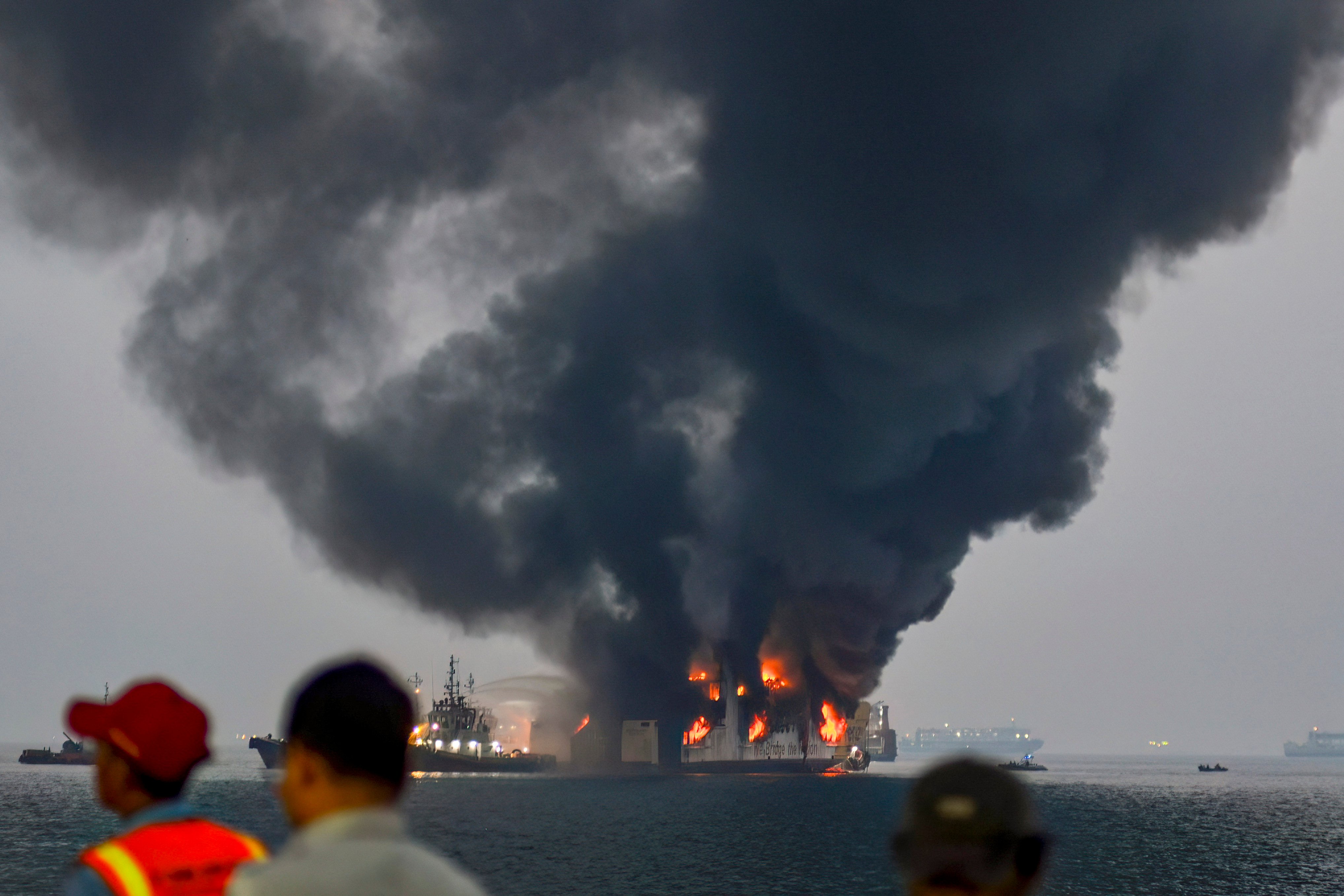 A fireboat (background centre L) pumps water over the burning KMP Batumandi ferry after it caught fire in waters off Merak in Cilegon, Banten province on October 20, 2026. (Photo by RONALD SIAGIAN / AFP)