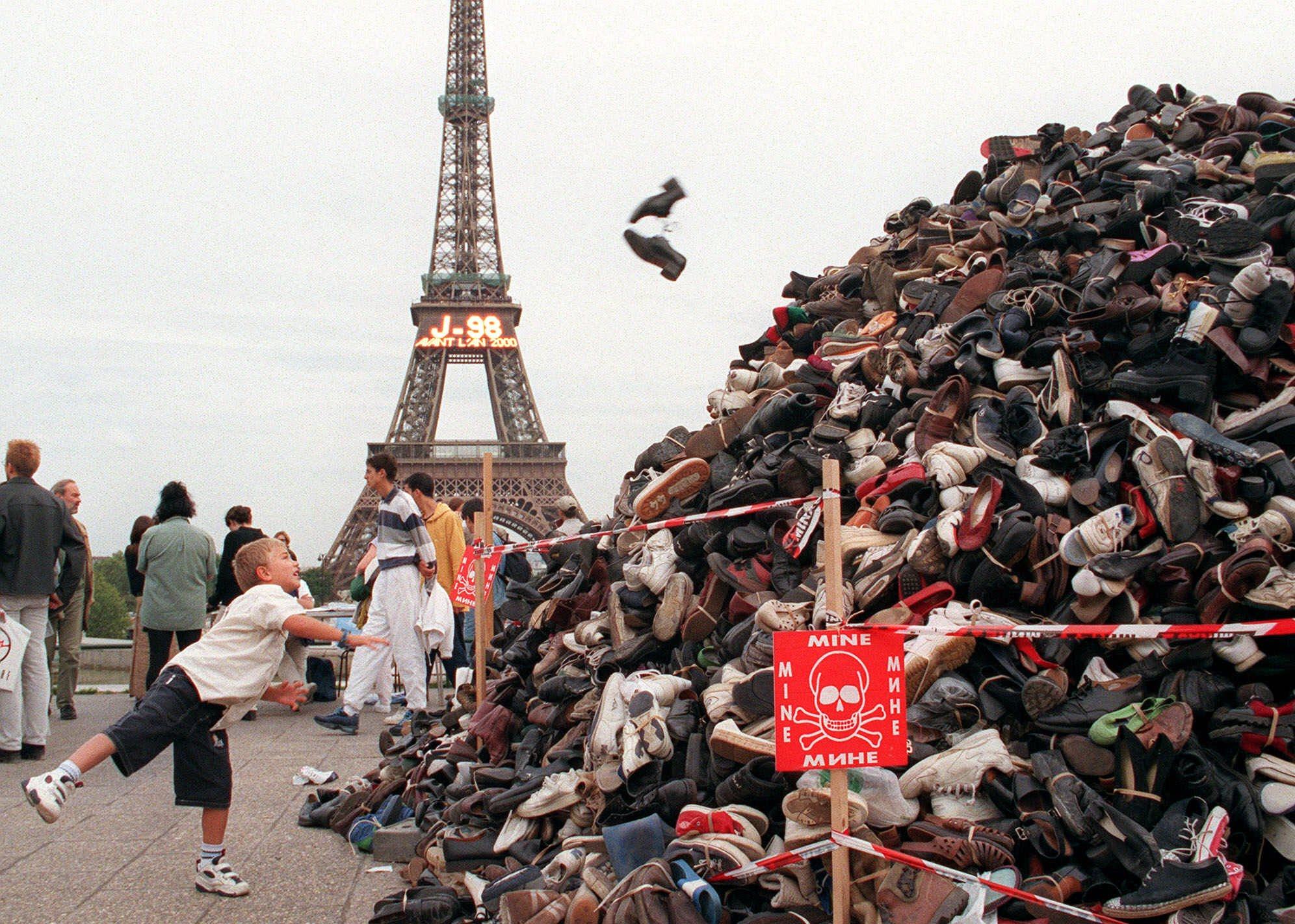 A boy tosses shoes onto a massive pyramid of footwear near the Eiffel Tower during a September 1999 demonstration against landmines. Photo: AP