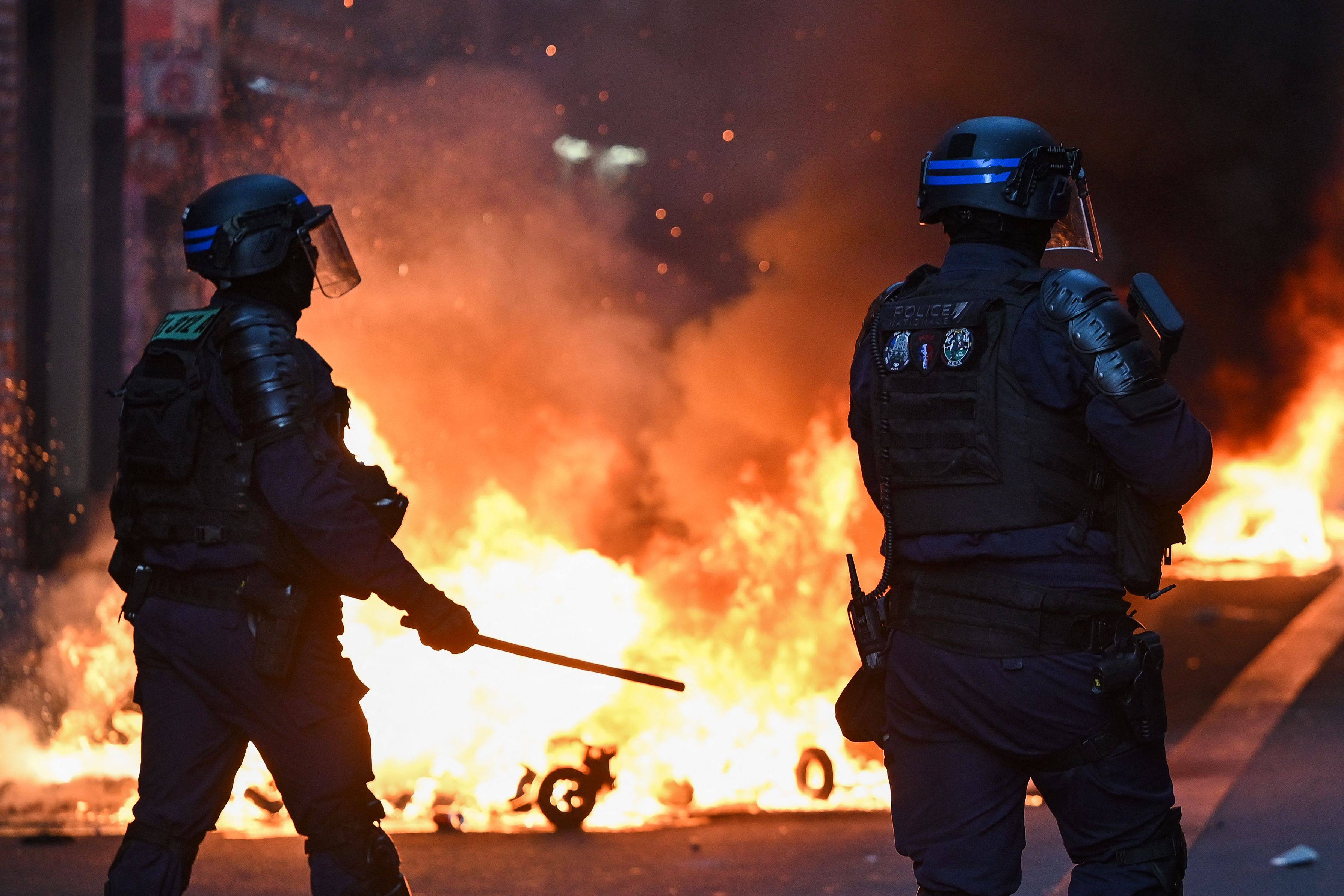 French Republican Security Corps officers stand in front of a fire in rue du Faubourg du Temple in Place de la Republique as clashes erupt in central Paris on October 18. Photo: AFP