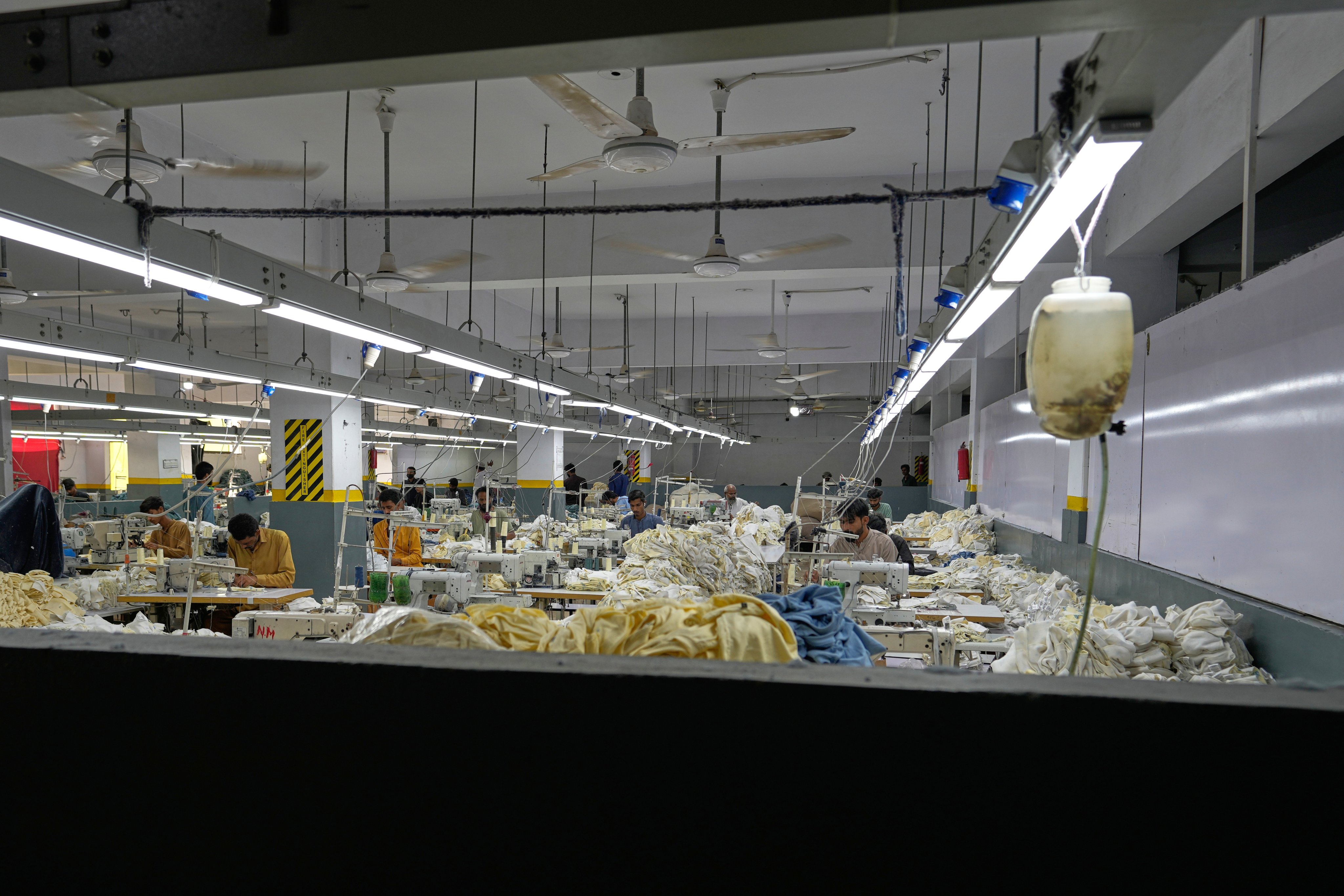 Workers stitch clothes at a factory with fans in Karachi on Octpber 2. Photo: AP