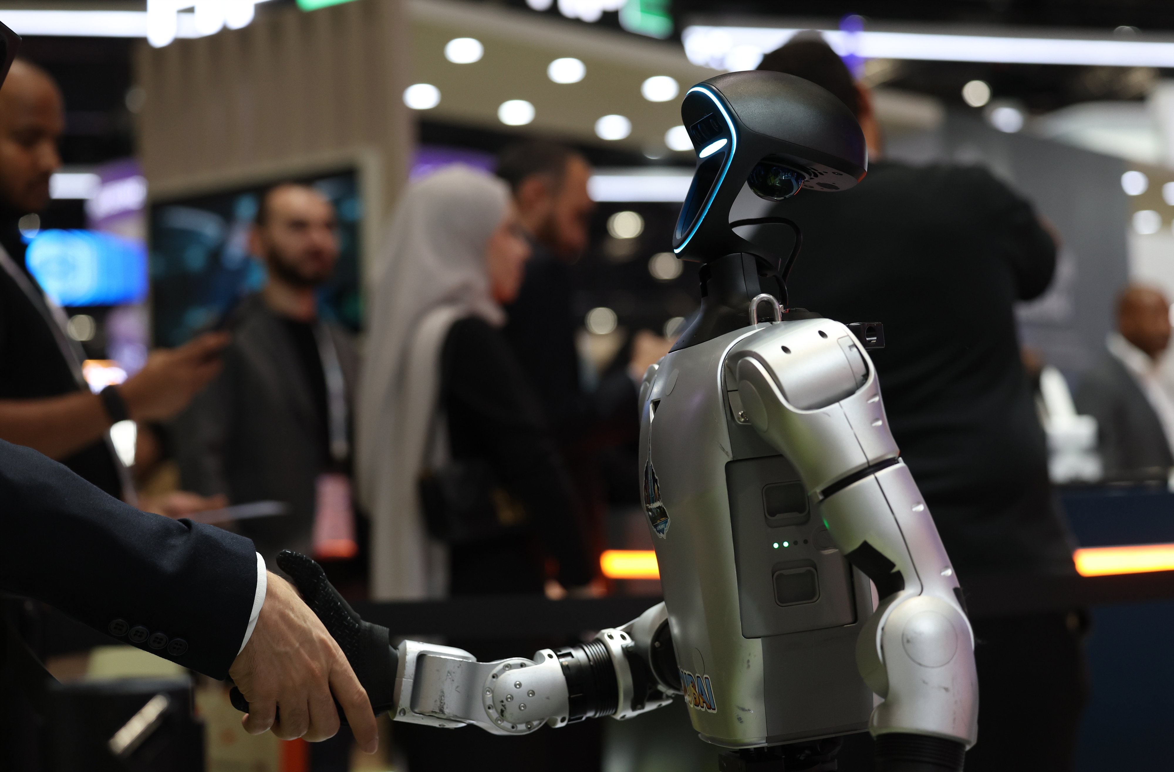 A visitor shakes hands with a robot at the AI Everything Abu Dhabi conference and exhibition in Abu Dhabi, United Arab Emirates, on October 6. Photo: EPA