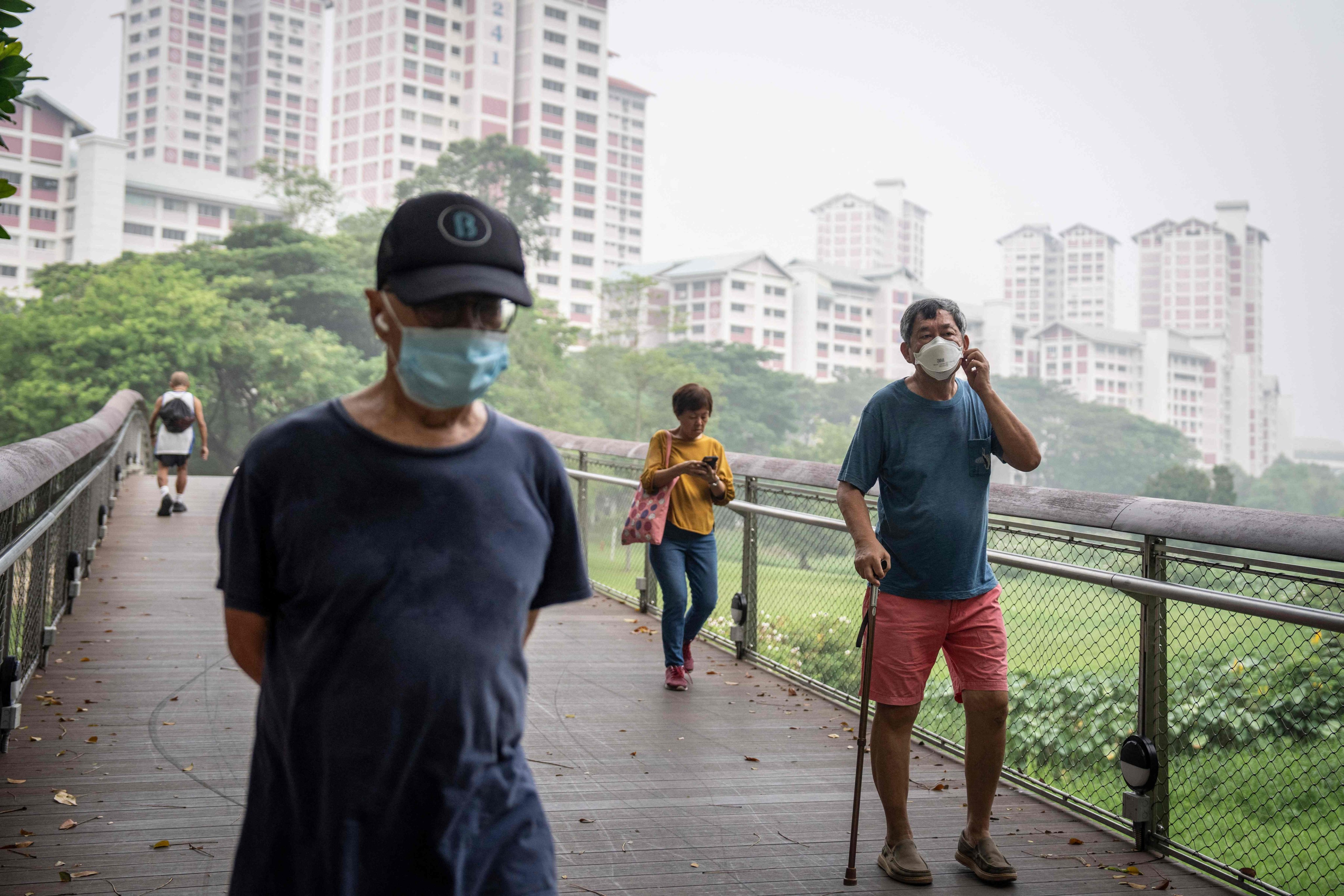 People wearing face masks walk past a public housing block in Singapore on Sunday, as haze from Indonesian wildfires triggers high-level alerts. Photo: AFP