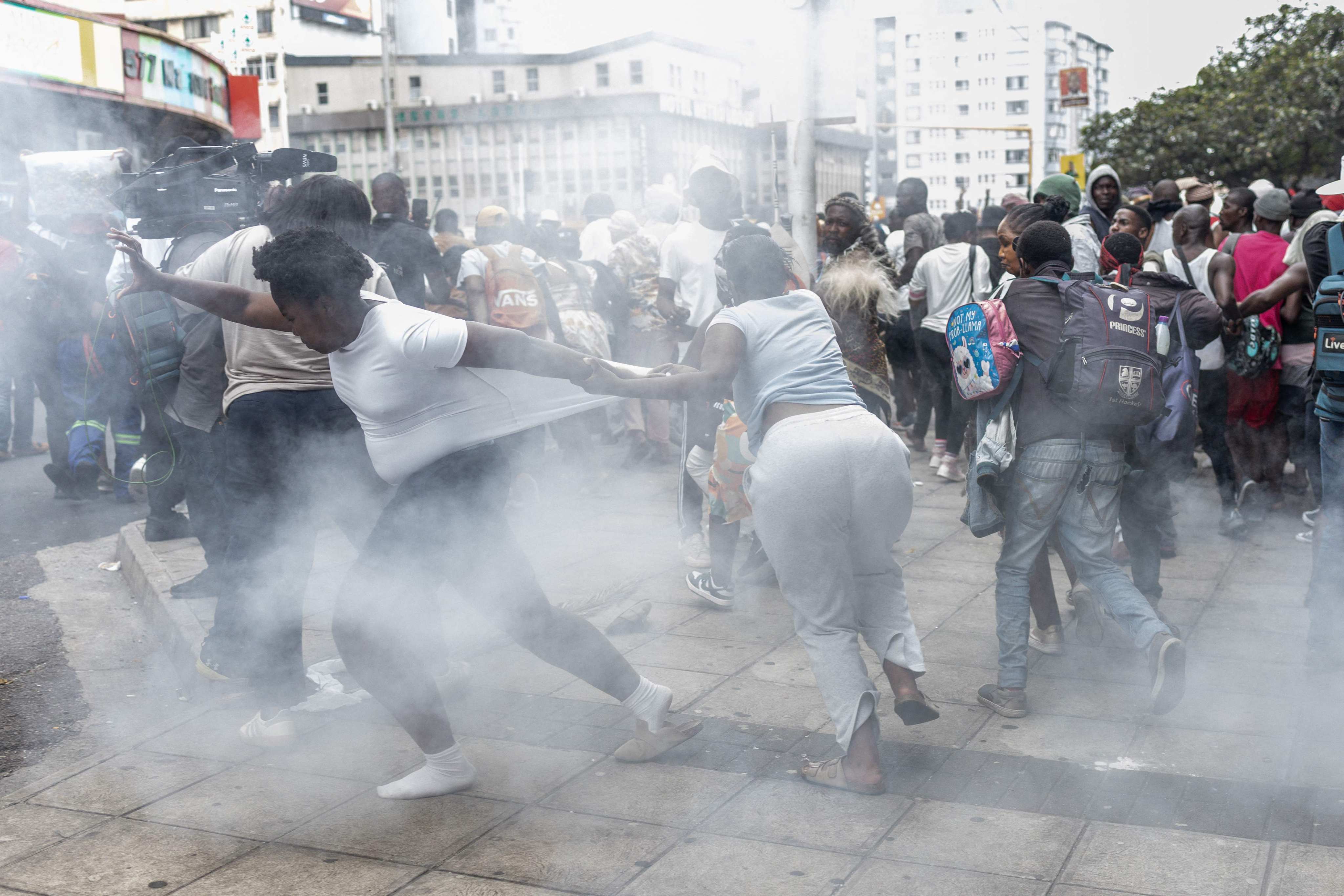 Members of the public react to a stun grenade fired during an anti-migrant march in Durban on October 9. Photo: AFP