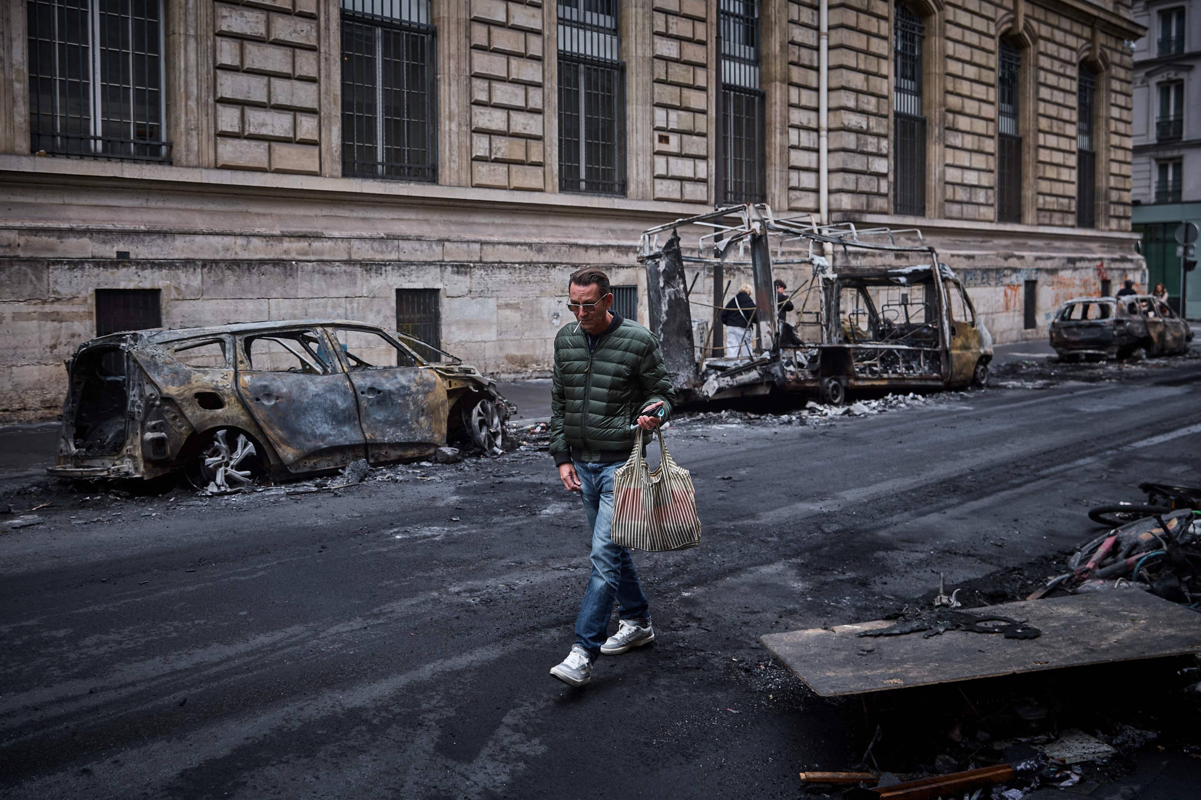 A man walks past burnt-out vehicles in Paris on Monday. Photo: AFP/dpa