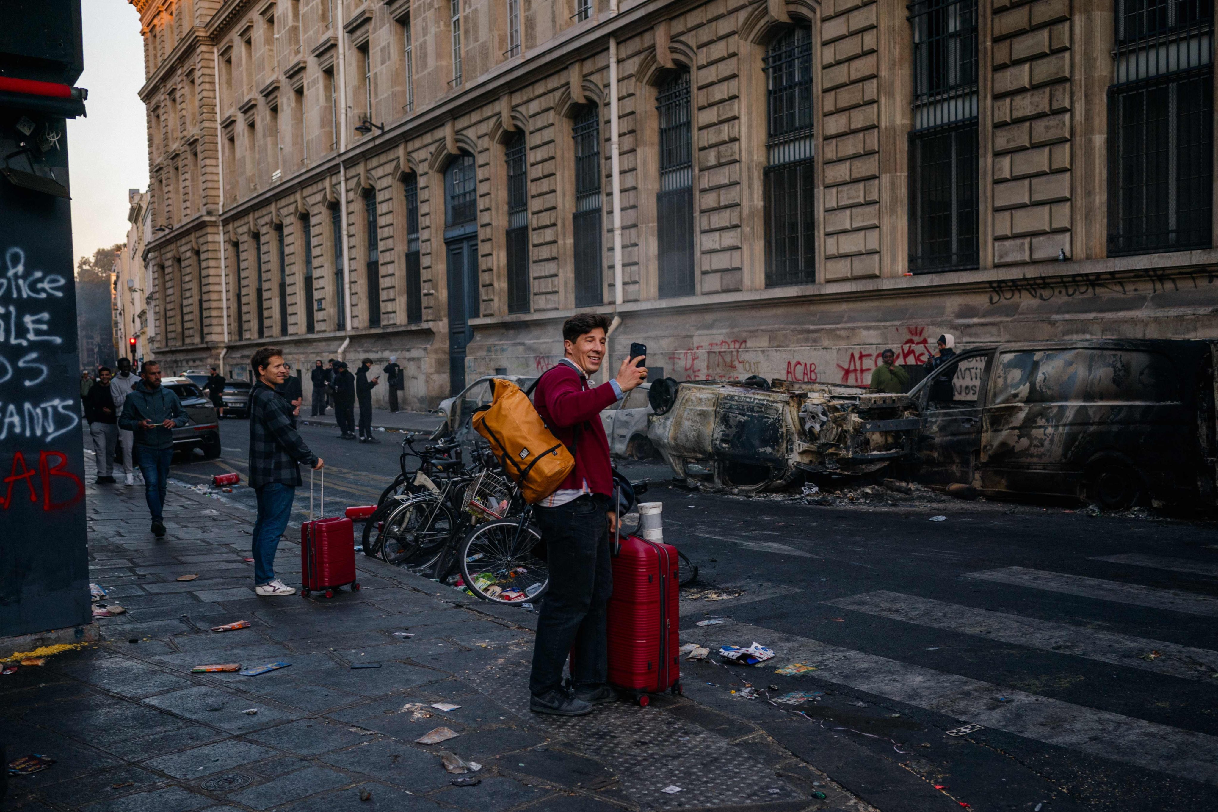 A tourist uses his smartphone to film burnt cars in Paris, France, on Saturday. Photo: AFP
