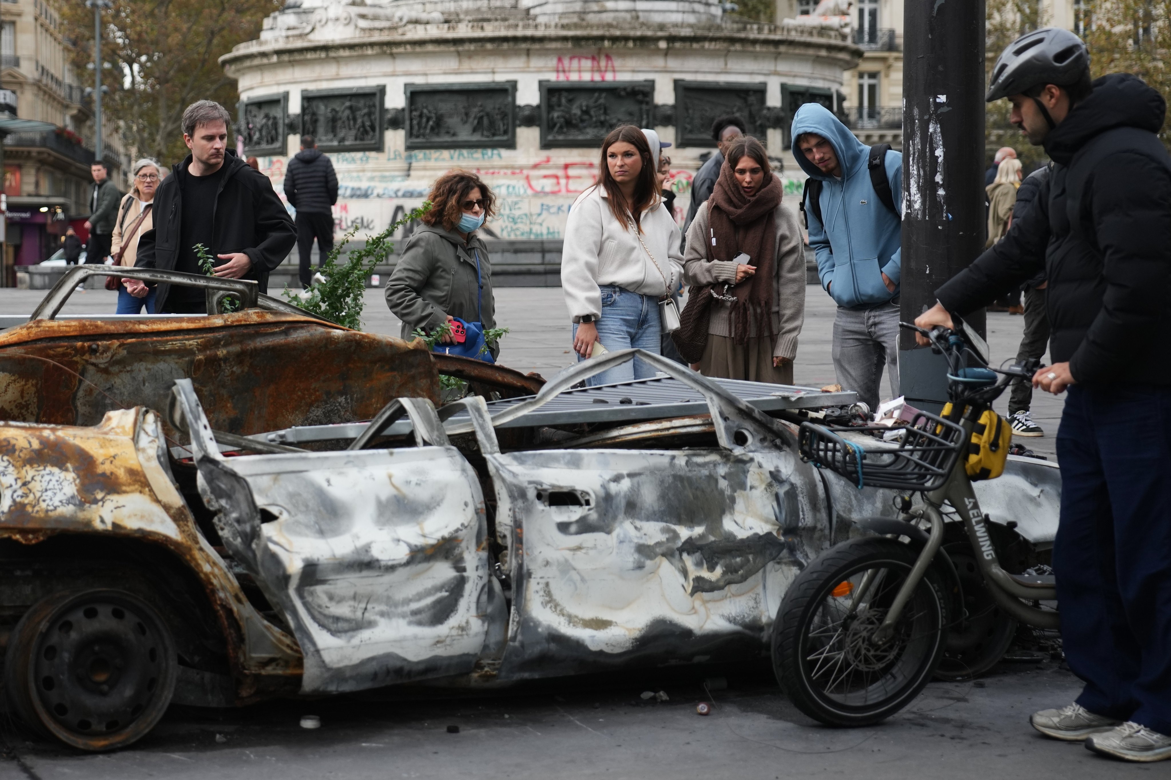 People look at a burned-out car after a quiet night under curfew, the first since weekend protests over the cost of living turned into rioting and looting across France, in Paris on October 20. Photo: AP