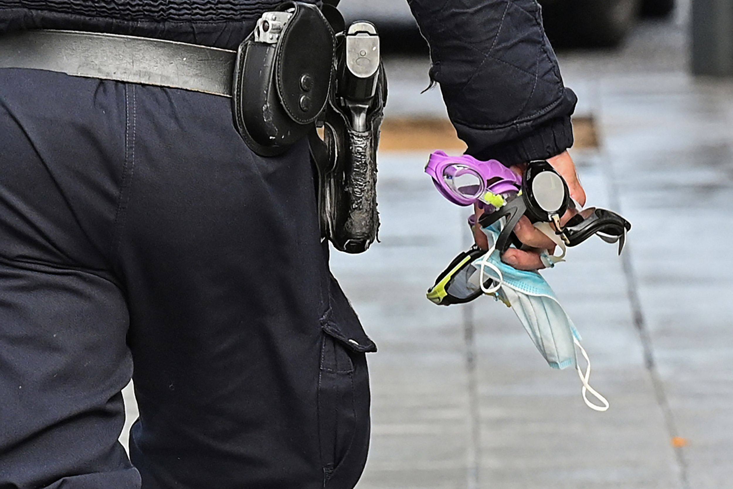 A French police officer in Toulouse holds demonstrators’ confiscated items including swimming goggles. Photo: AFP