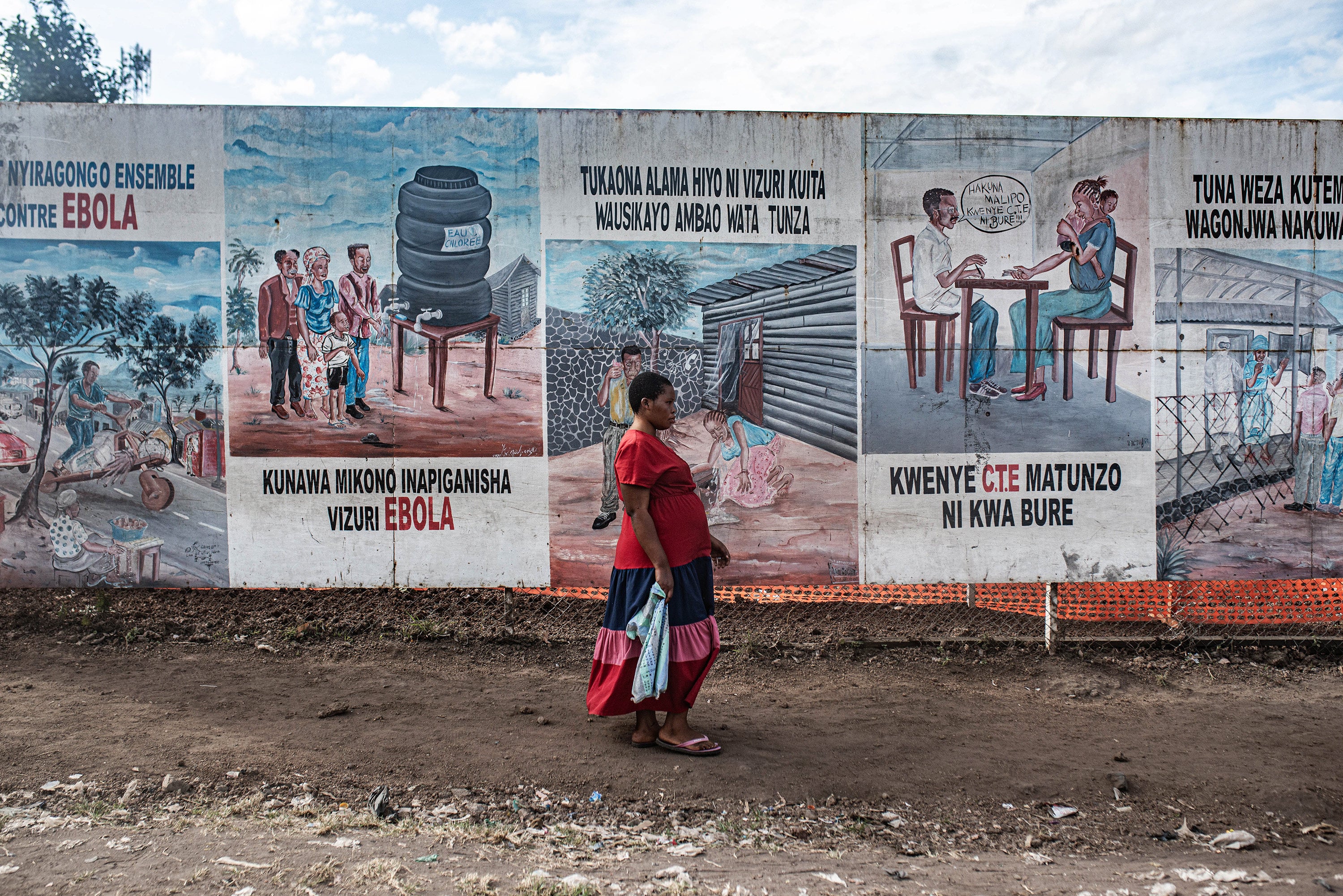 A woman walks by posters warning about Ebola near an Ebola treatment center on June 2, in Monigi, Democratic Republic of Congo. Photo: TNS