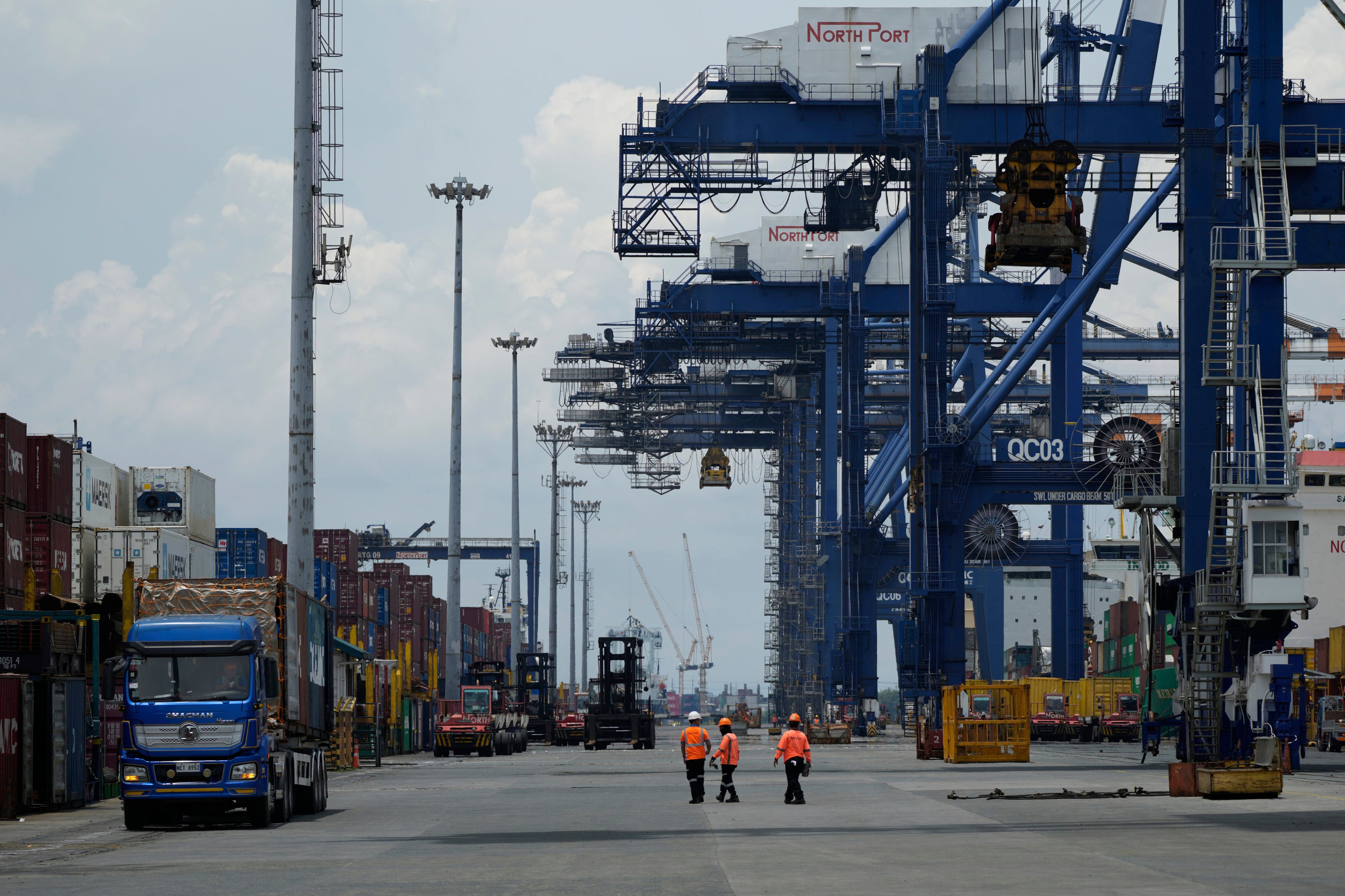 Workers walk beside containers at the Manila North Harbour Port in the Philippines. Photo: AP