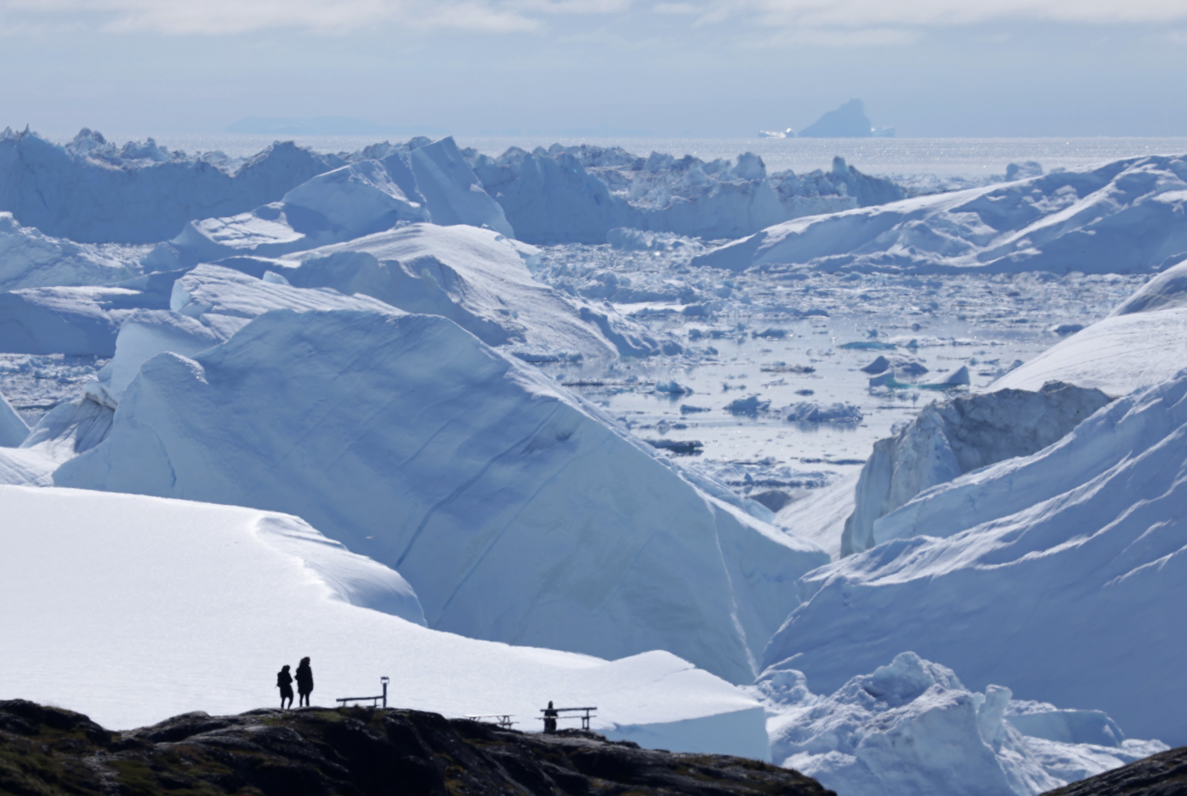 Visitors look out at melting icebergs near Ilulissat, Greenland, in July 2024. Photo: Getty Images