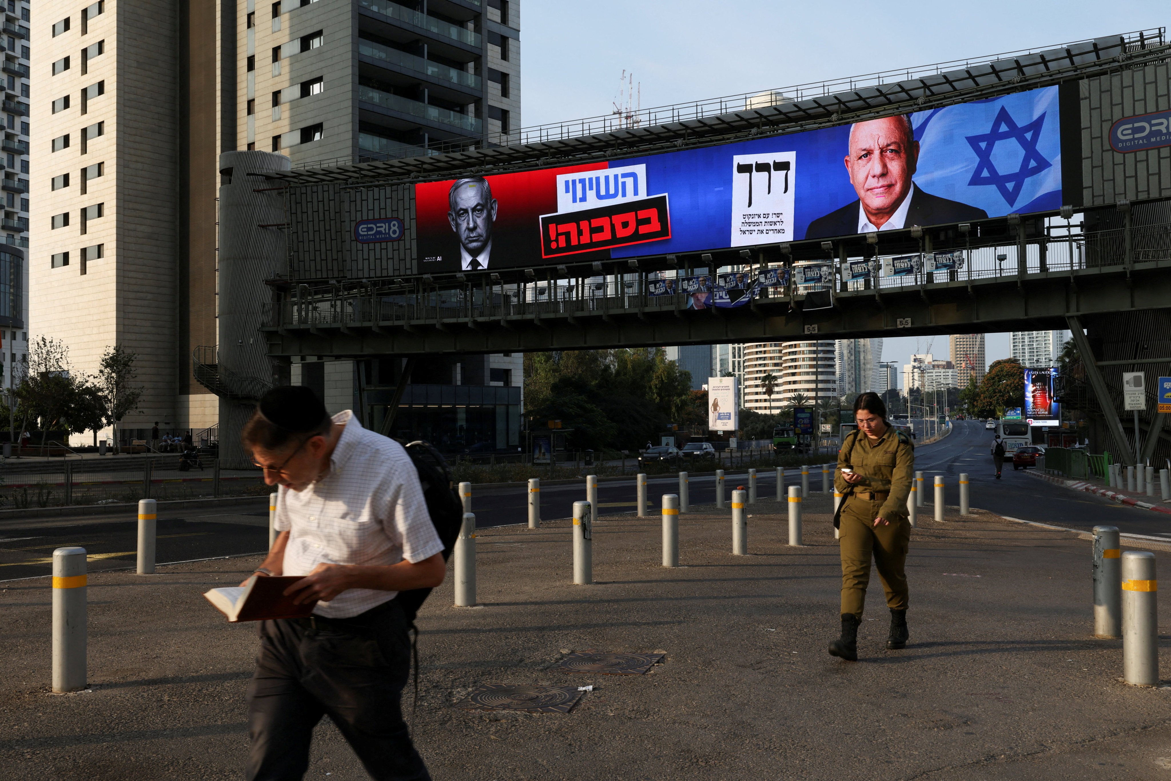 Pedestrians walk past a campaign billboard featuring Prime Minister Benjamin Netanyahu and challenger Gadi Eisenkot as Israelis head to the polls on Tuesday. Photo: AP