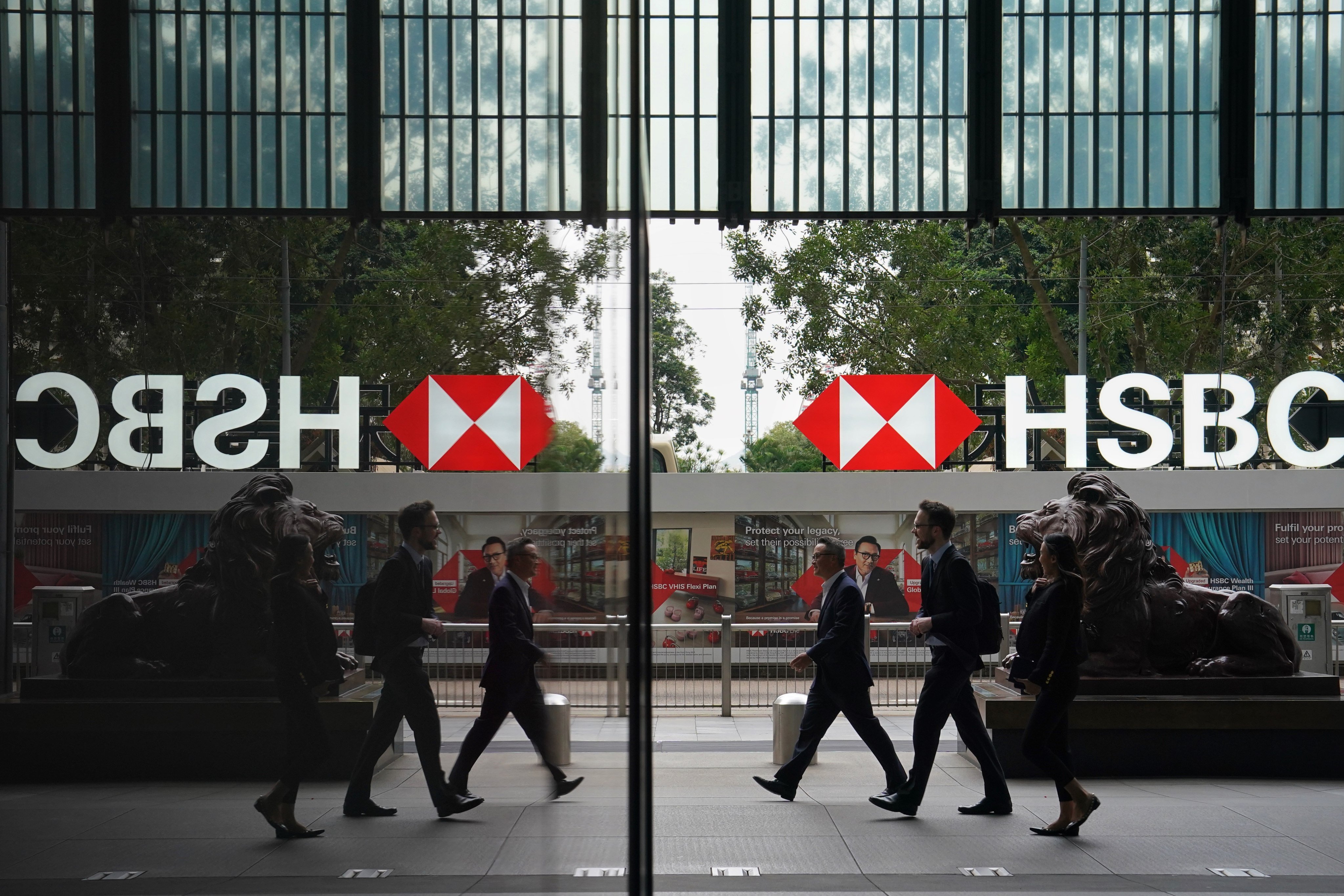 Pedestrians walk past the lion statues outside HSBC’s Hong Kong head office in Central. Photo: Elson Li