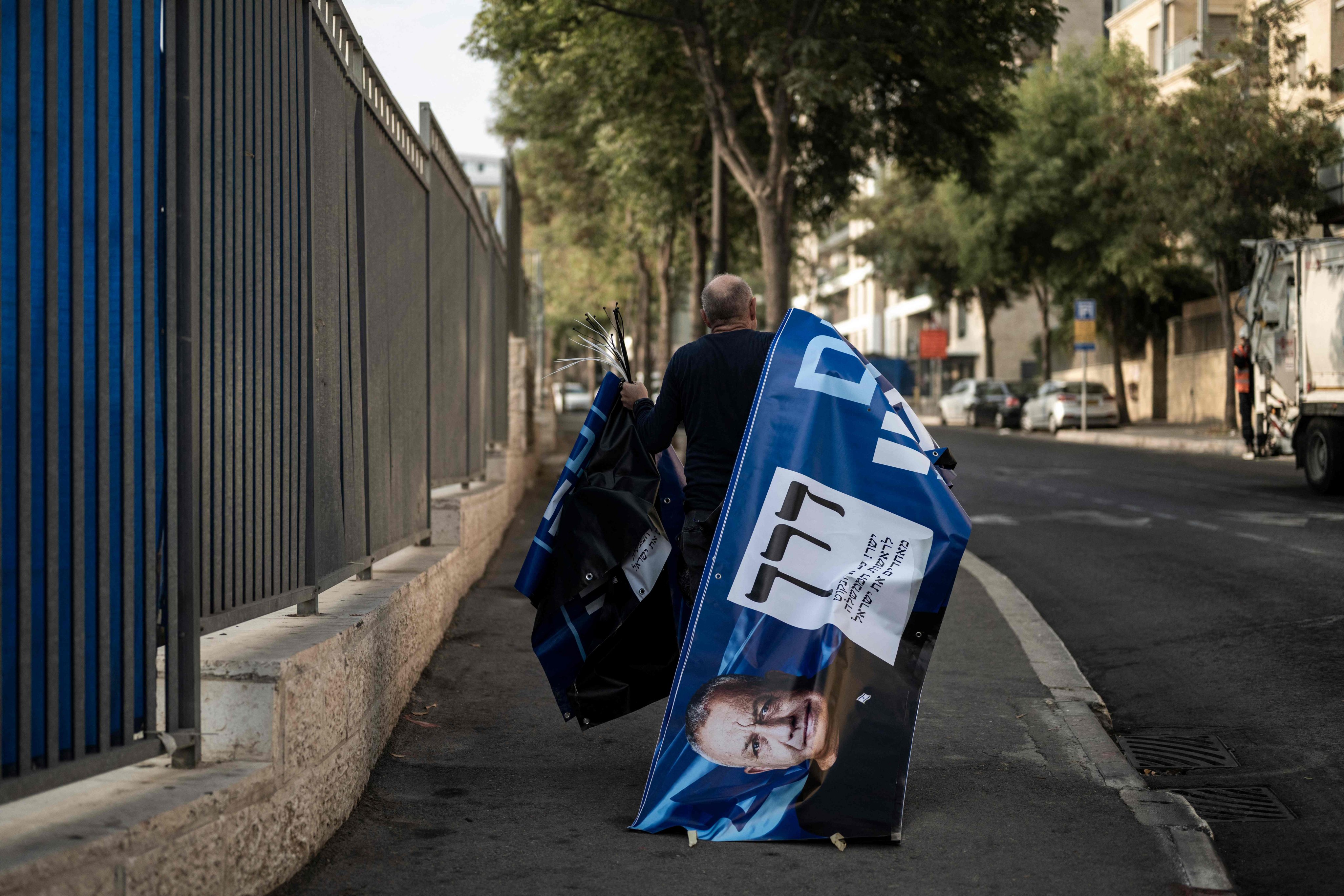 A supporter of the Yashar party, led by Gadi Eisenkot, carries electoral banners outside a polling station in Jerusalem. Photo: AFP